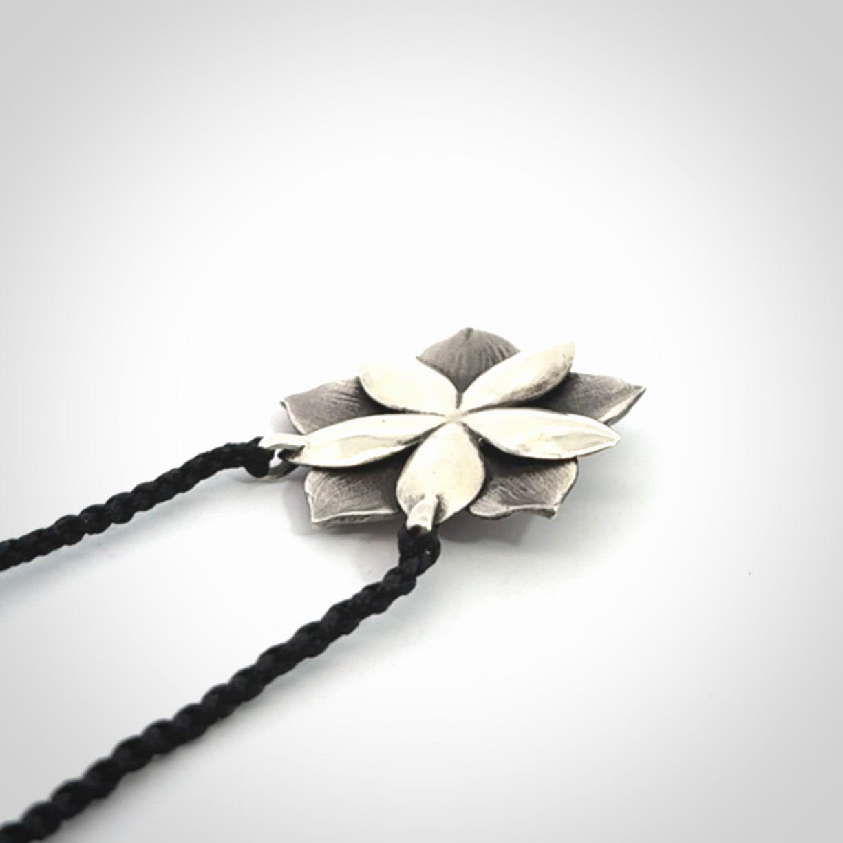 This is a hand carved Sterling Silver Manuka Flower pendant with New Zealand Jade insert. This is a medium sized necklace and is provided with an adjustable black cord.