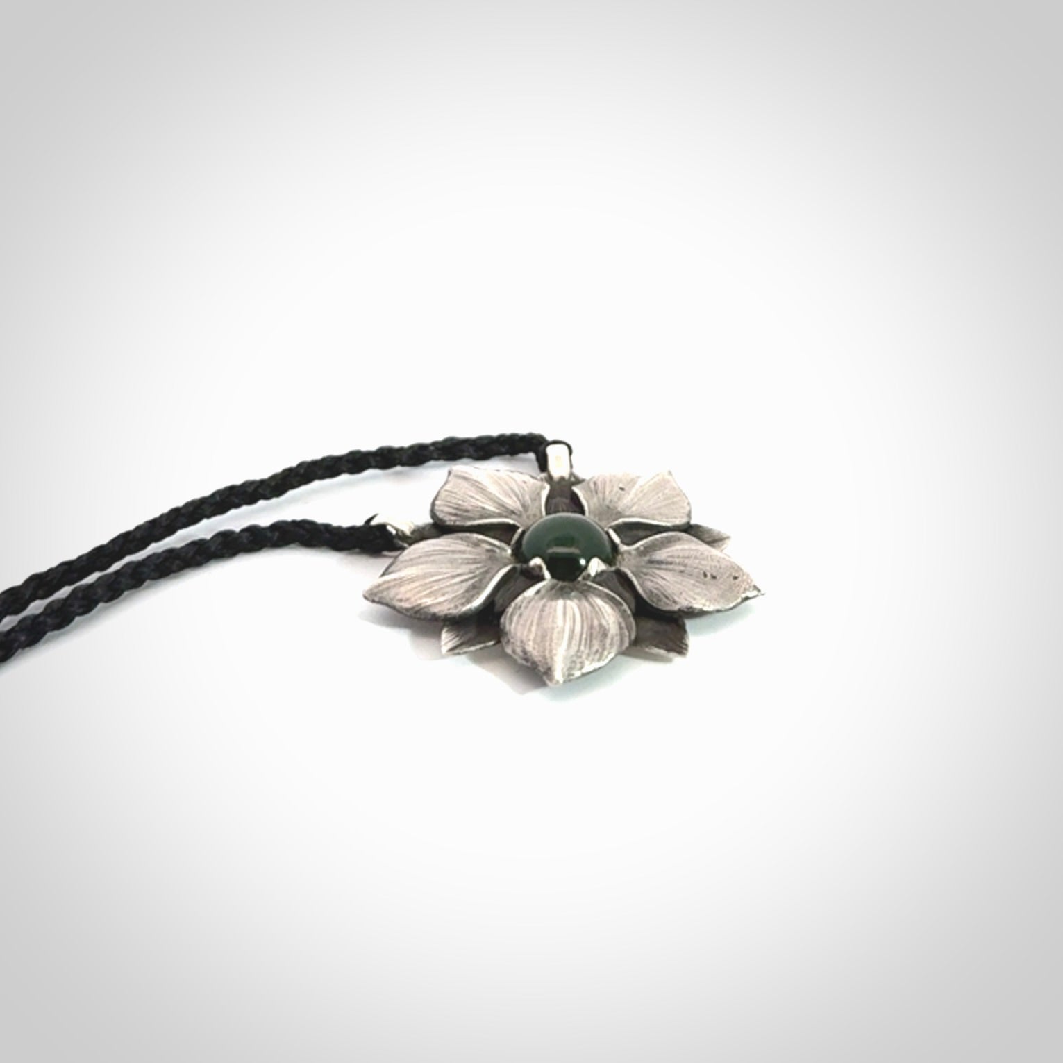This is a hand carved Sterling Silver Manuka Flower pendant with New Zealand Jade insert. This is a medium sized necklace and is provided with an adjustable black cord.