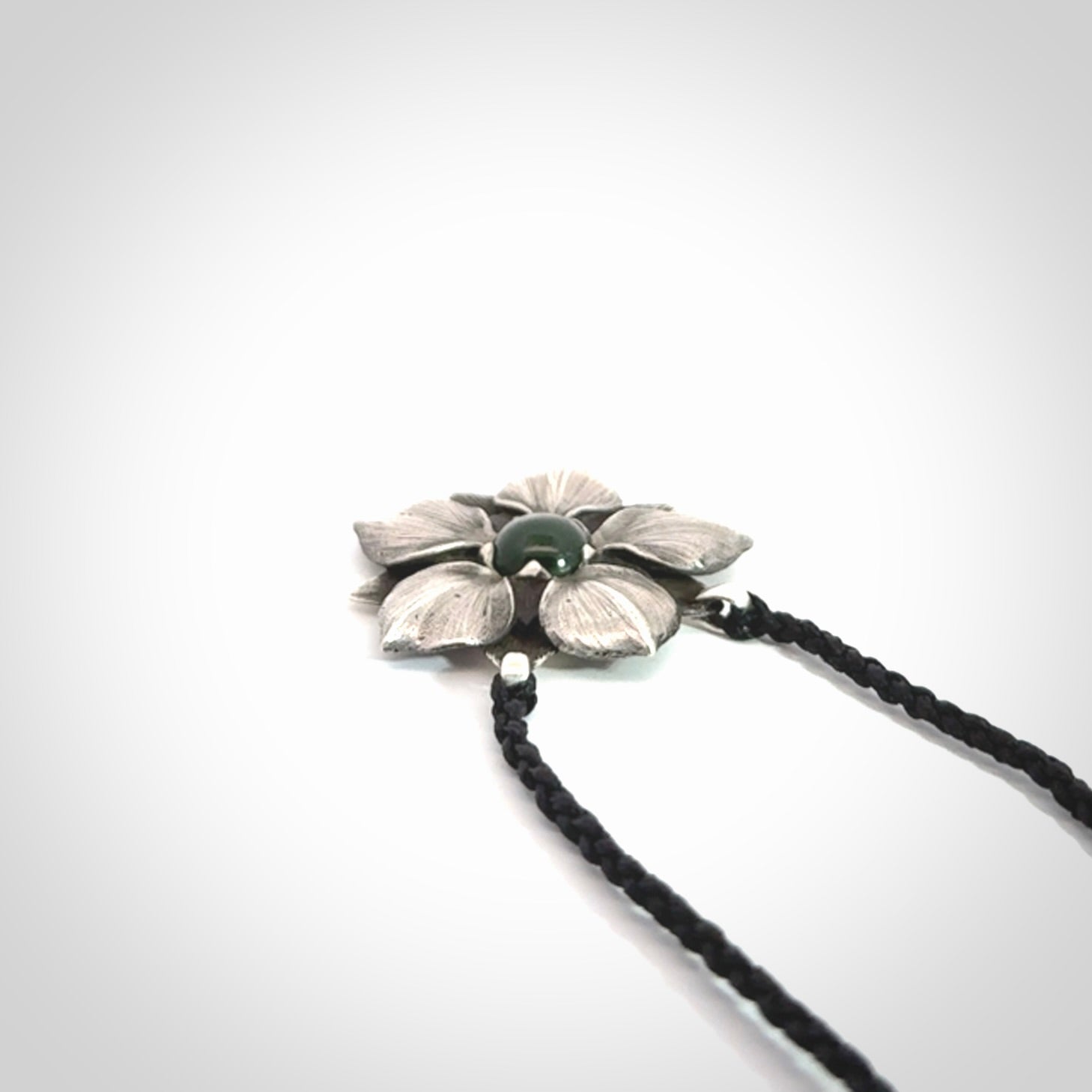 This is a hand carved Sterling Silver Manuka Flower pendant with New Zealand Jade insert. This is a medium sized necklace and is provided with an adjustable black cord.