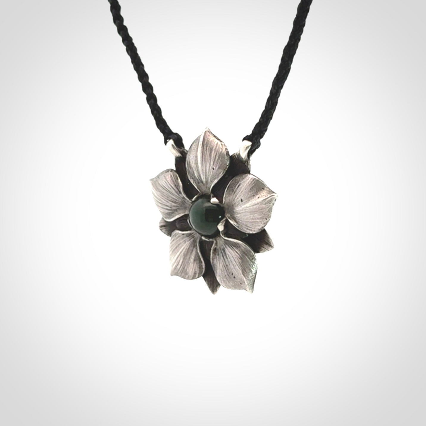 This is a hand carved Sterling Silver Manuka Flower pendant with New Zealand Jade insert. This is a medium sized necklace and is provided with an adjustable black cord.