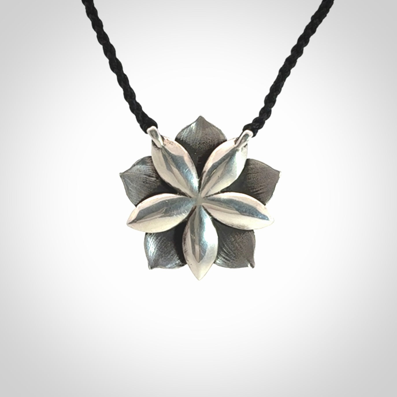 This is a hand carved Sterling Silver Manuka Flower pendant with New Zealand Jade insert. This is a medium sized necklace and is provided with an adjustable black cord.