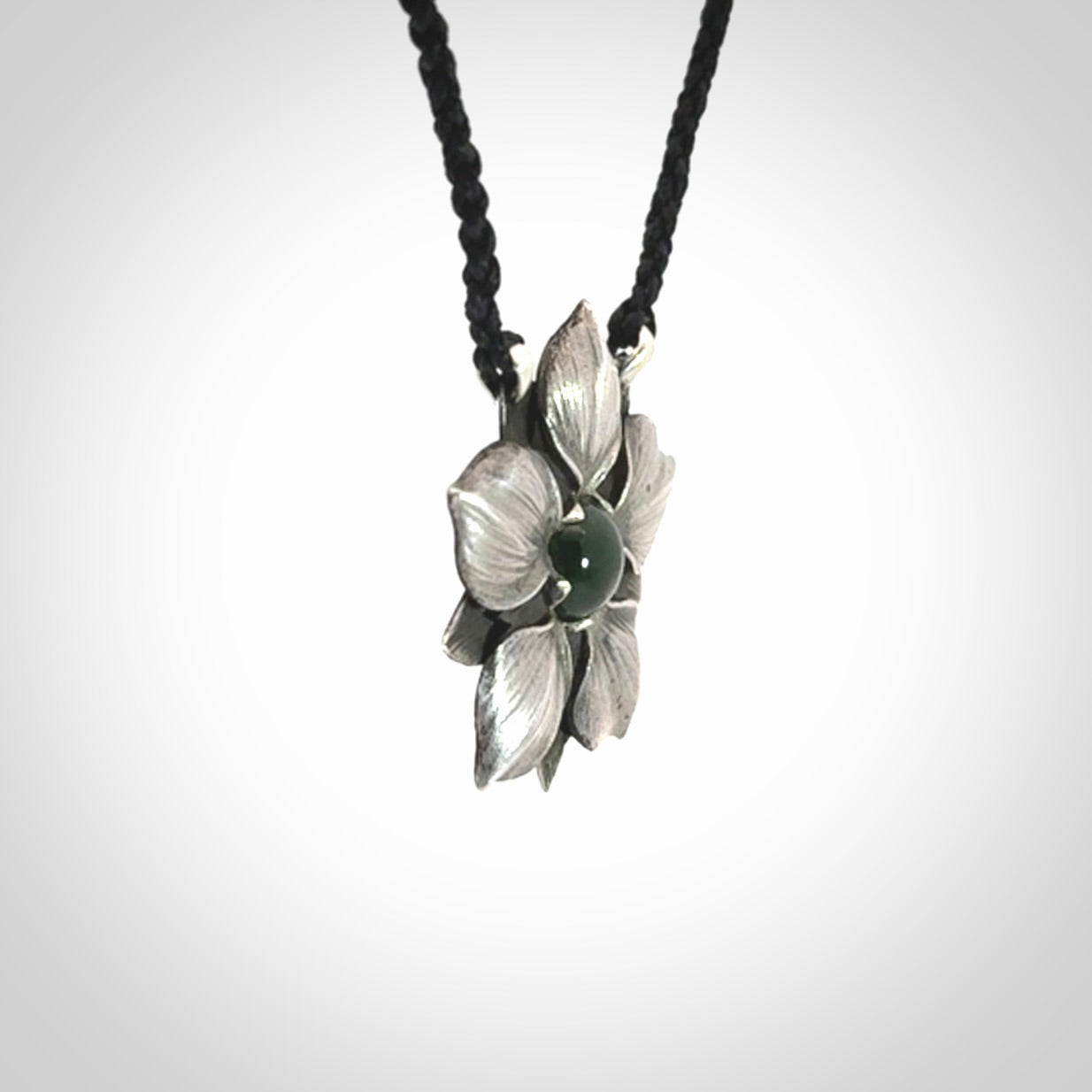 This is a hand carved Sterling Silver Manuka Flower pendant with New Zealand Jade insert. This is a medium sized necklace and is provided with an adjustable black cord.