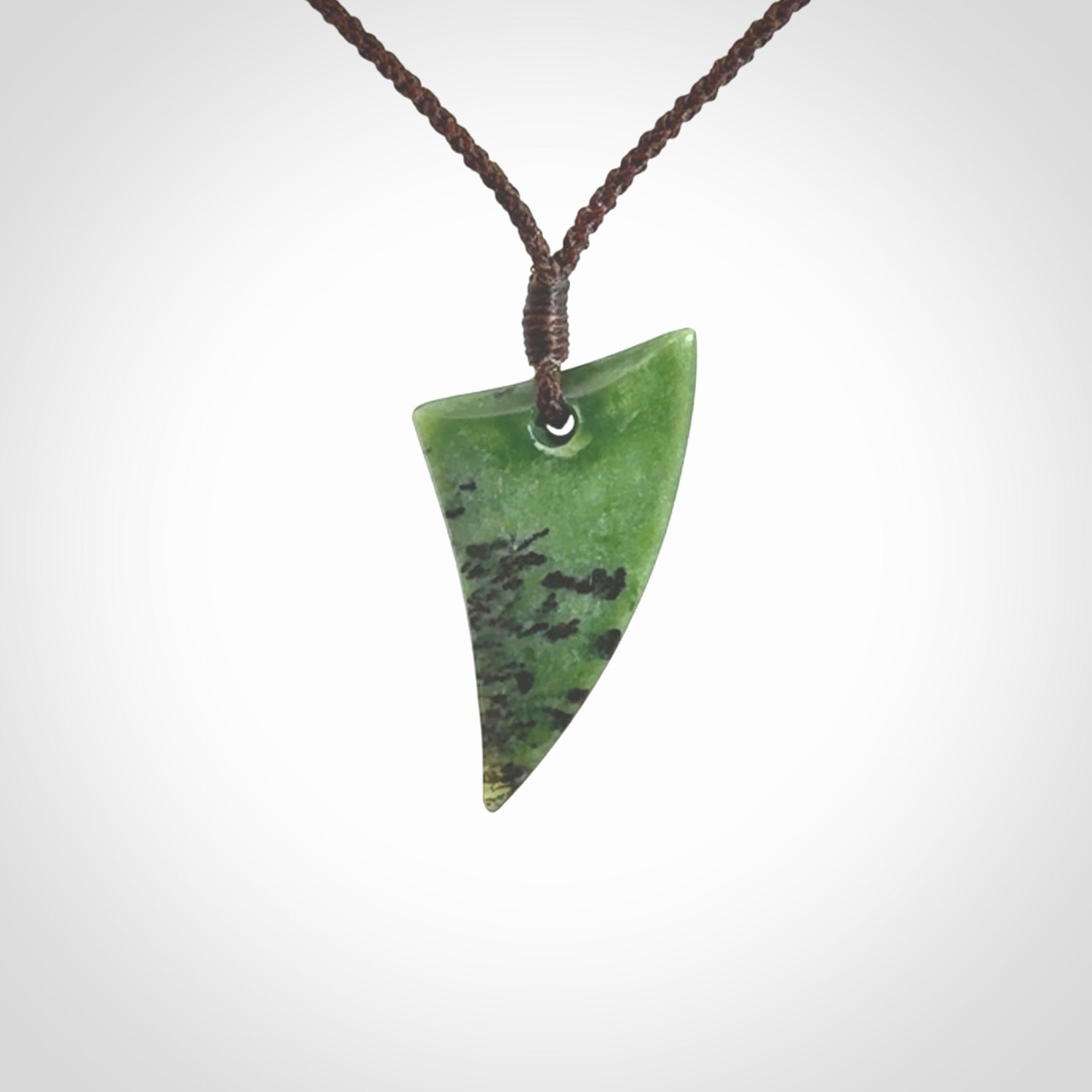 This is a lovely New Zealand Jade, pounamu niho drop pendant. Hand carved for us by Ric Moor. It is bound with an adjustable brown coloured cord which is length adjustable. Free worldwide shipping.