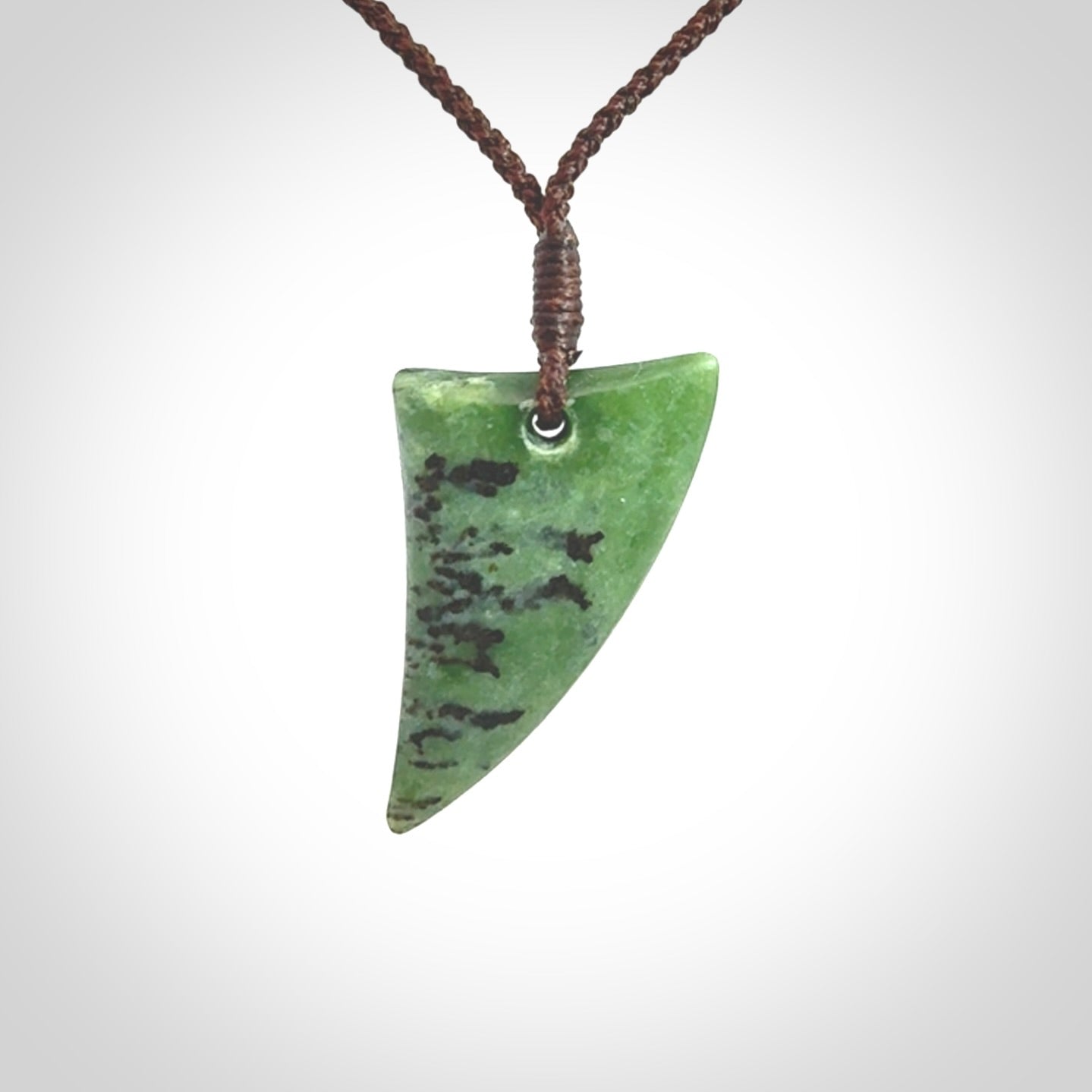 This is a lovely New Zealand Jade, pounamu niho drop pendant. Hand carved for us by Ric Moor. It is bound with an adjustable brown coloured cord which is length adjustable. Free worldwide shipping.