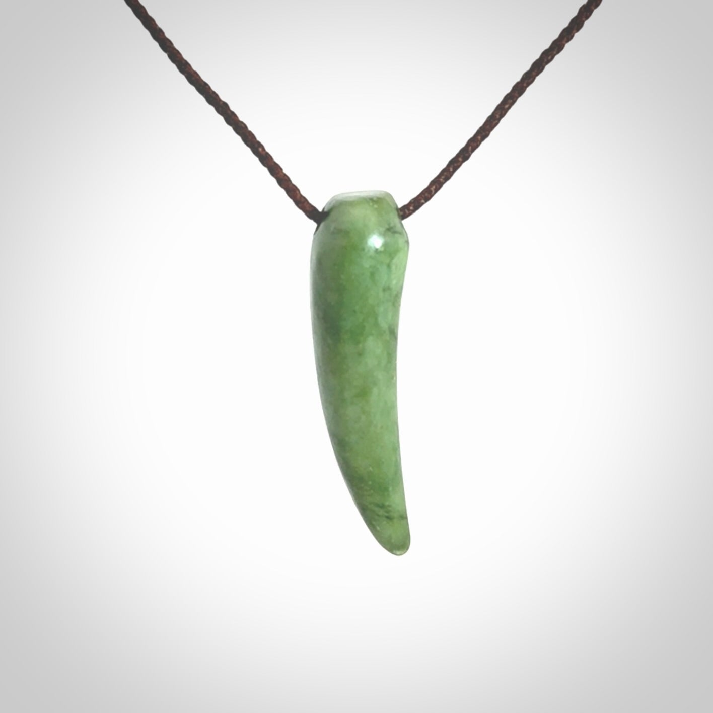 This is a lovely New Zealand Jade, pounamu niho drop pendant. Hand carved for us by Ric Moor. It is bound with an adjustable brown coloured cord which is length adjustable. Free worldwide shipping.