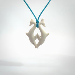 Hand carved natural double dolphin bone pendant. Hand made bone dolphin necklace, delivered with Express Courier. Hand crafted bone double dolphin pendant. Provided with an adjustable paradise blue cord.