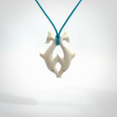 Hand carved natural double dolphin bone pendant. Hand made bone dolphin necklace, delivered with Express Courier. Hand crafted bone double dolphin pendant. Provided with an adjustable paradise blue cord.