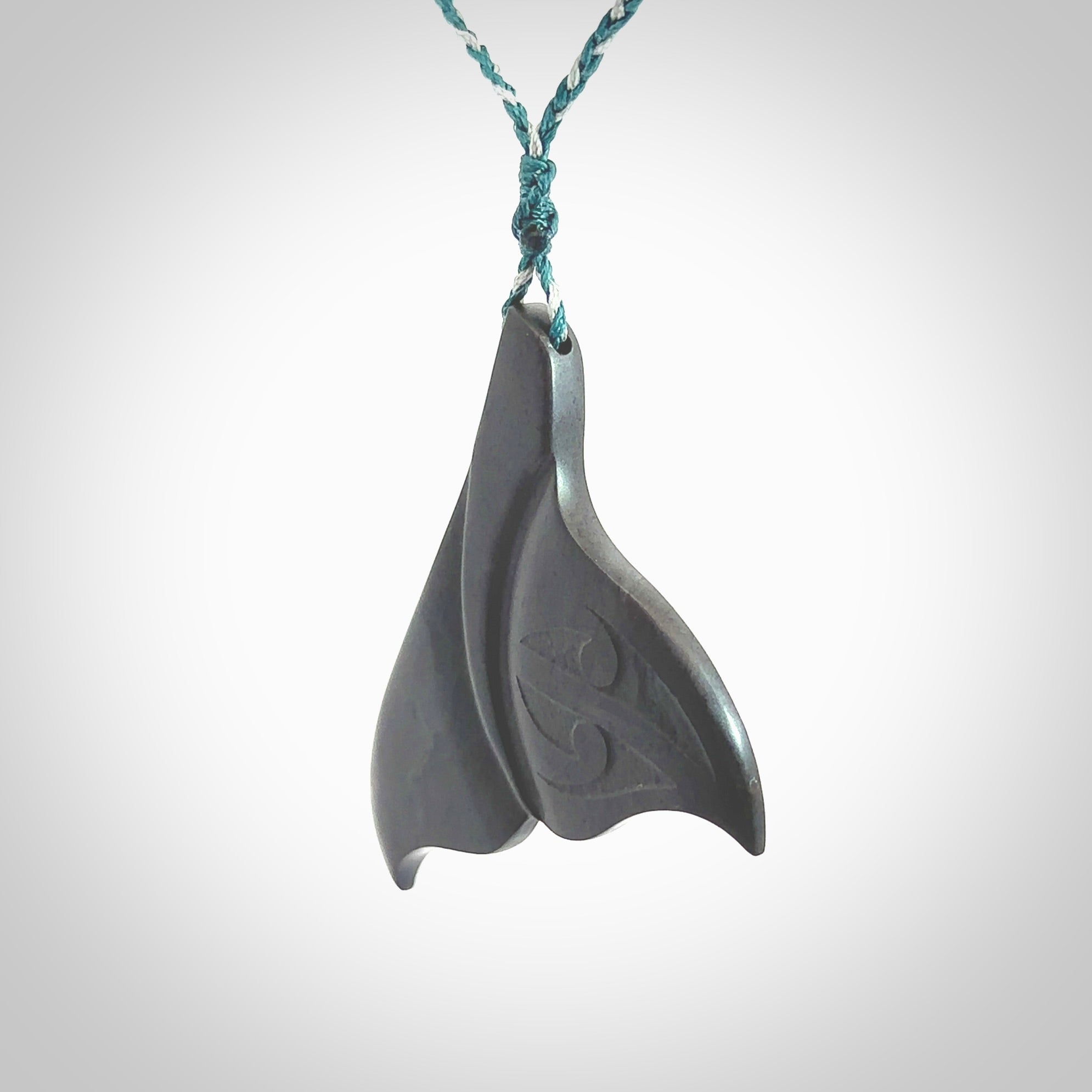 Hand carved New Zealand Argillite Stone whale tail pendant by Rueben Tipene. Hand made art to wear for lovers of the ocean. Delivered with express courier and delivered to you on an adjustable cord.