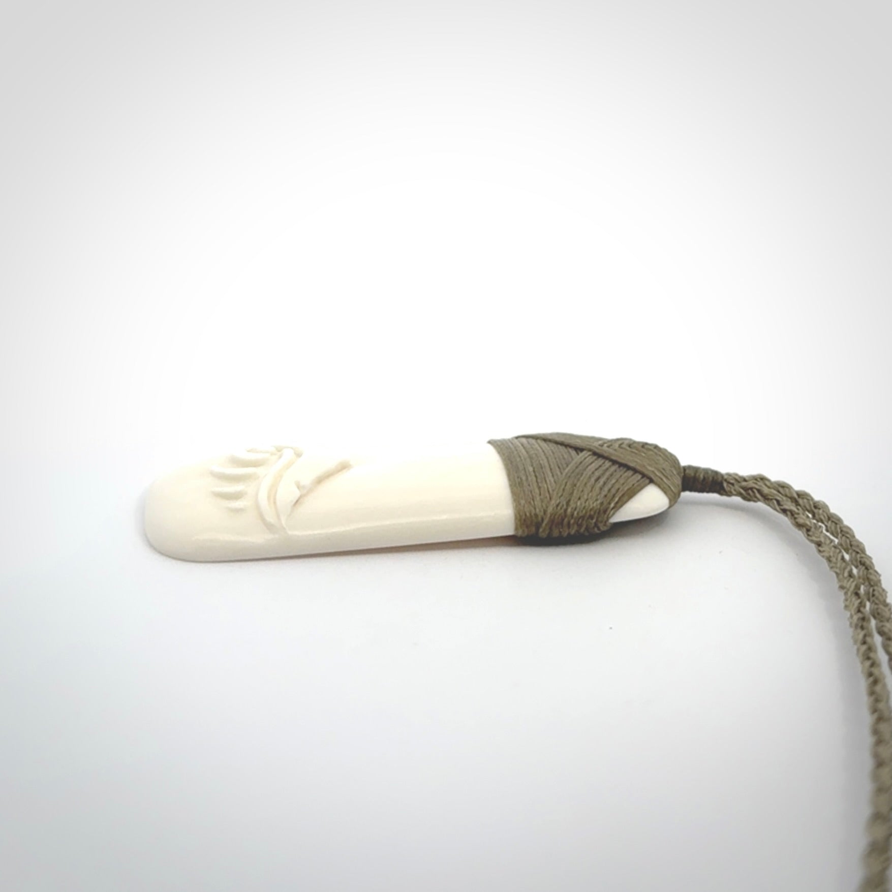 A hand carved bone toki with NZ Pacific logo engraving. Unique hand made jewellery from New Zealand Pacific.