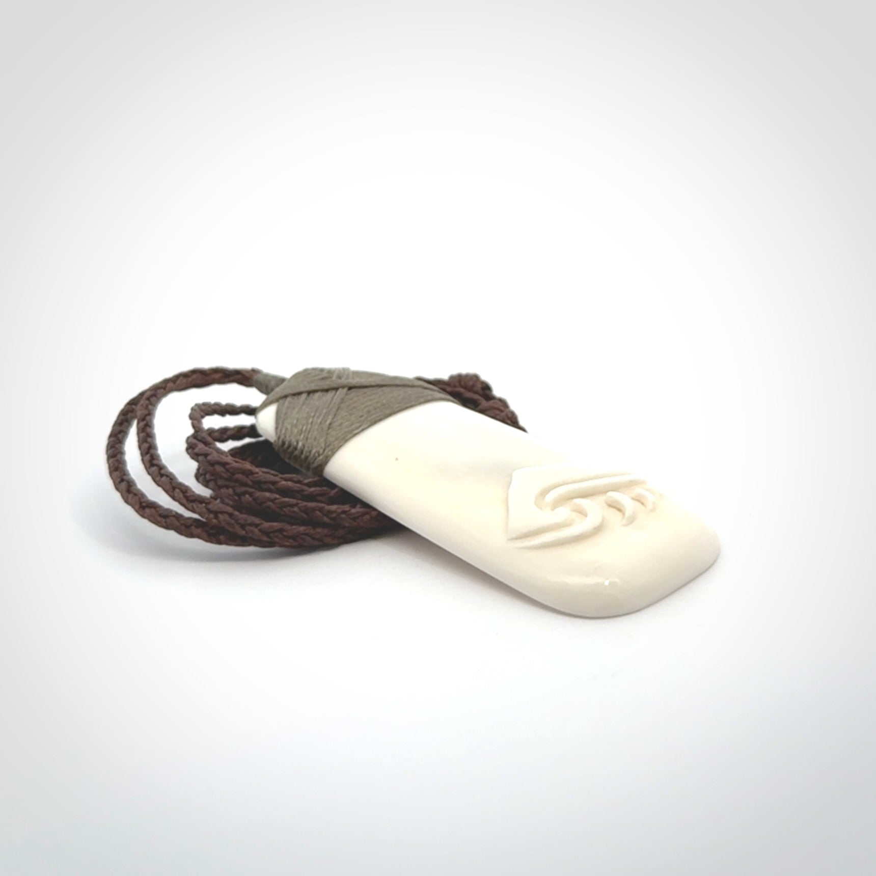 A hand carved bone toki with NZ Pacific logo engraving. Unique hand made jewellery from New Zealand Pacific.