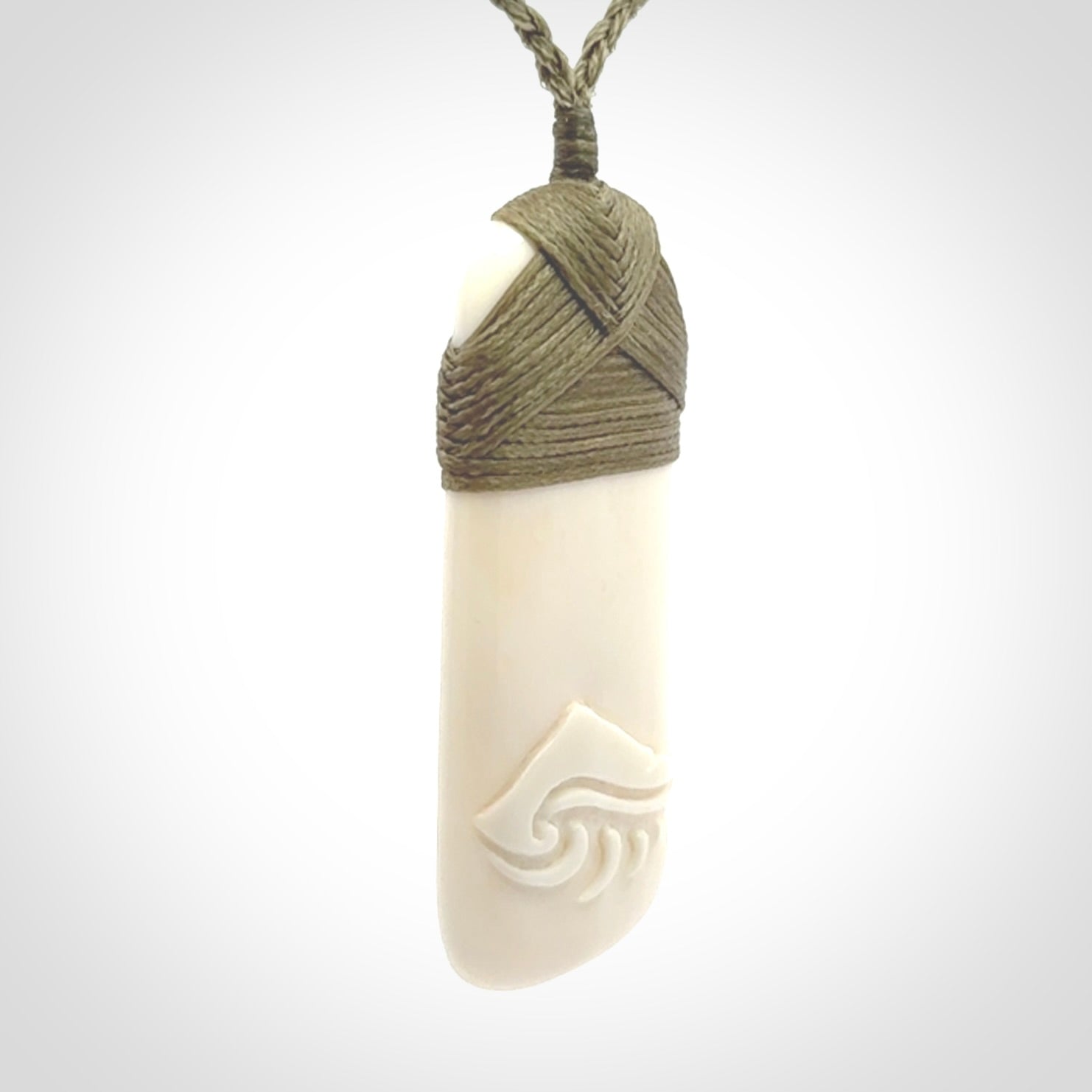 A hand carved bone toki with NZ Pacific logo engraving. Unique hand made jewellery from New Zealand Pacific.