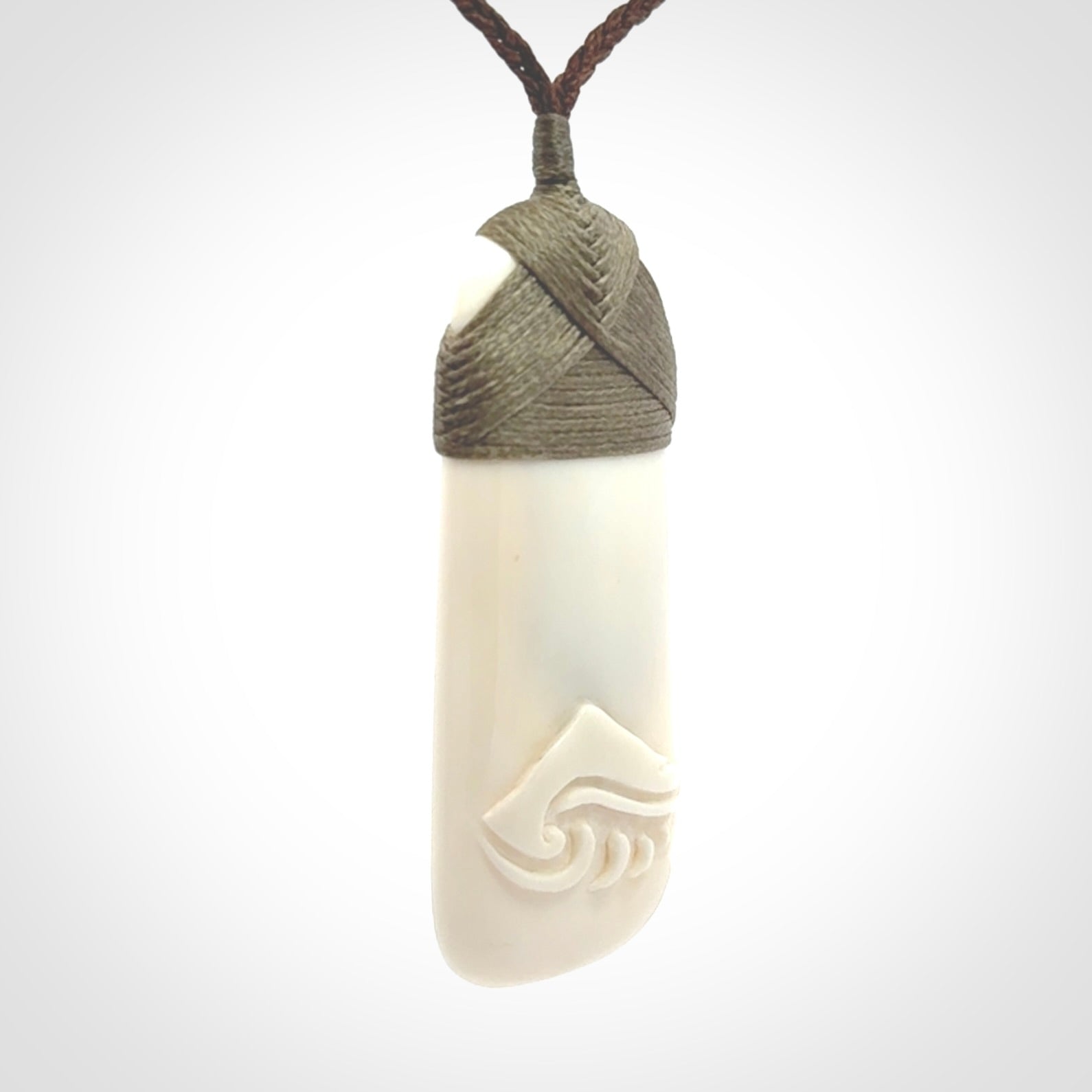 A hand carved bone toki with NZ Pacific logo engraving. Unique hand made jewellery from New Zealand Pacific.