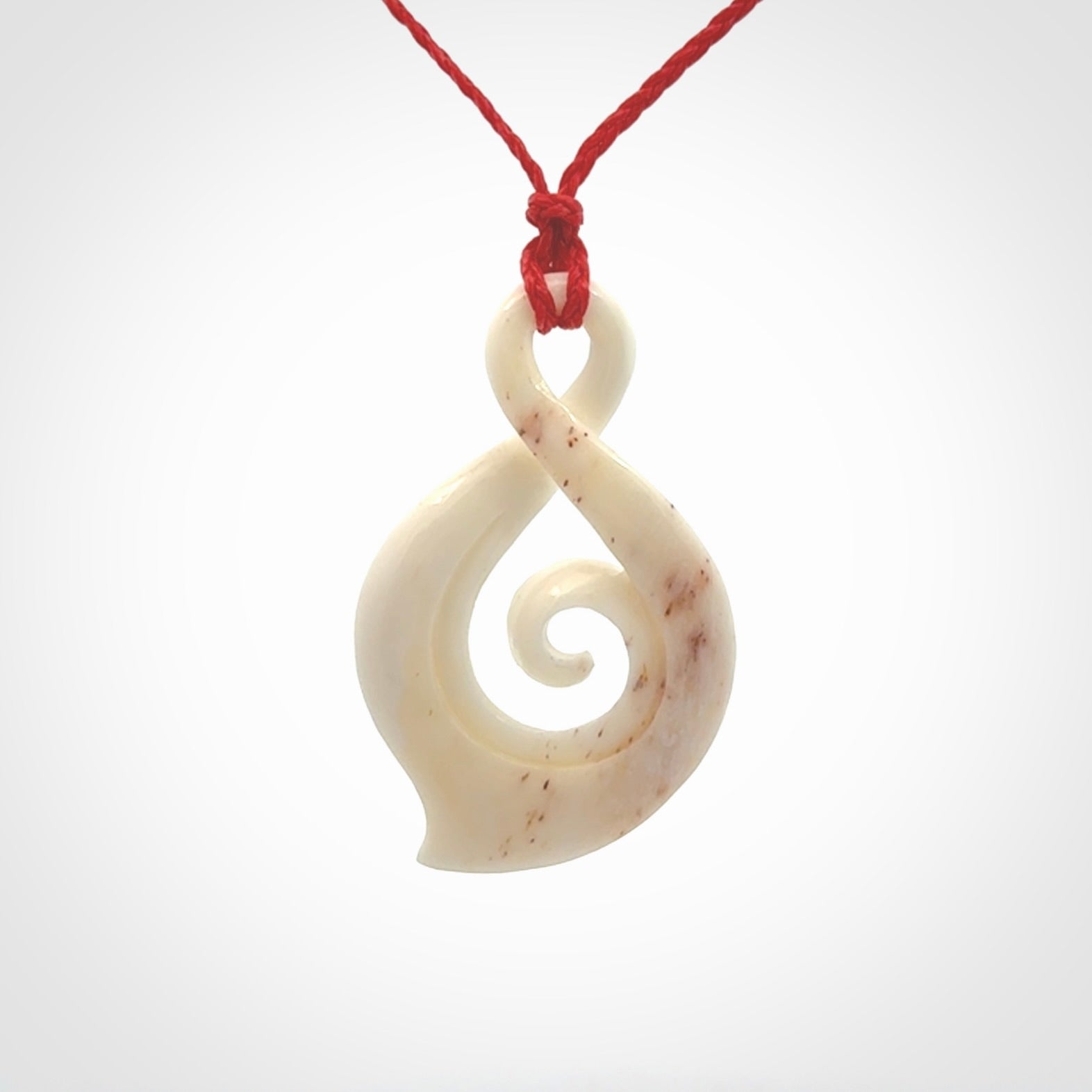 Hand carved twist with koru. Made from natural bone by NZ Pacific. Delivered with an adjustable cord.