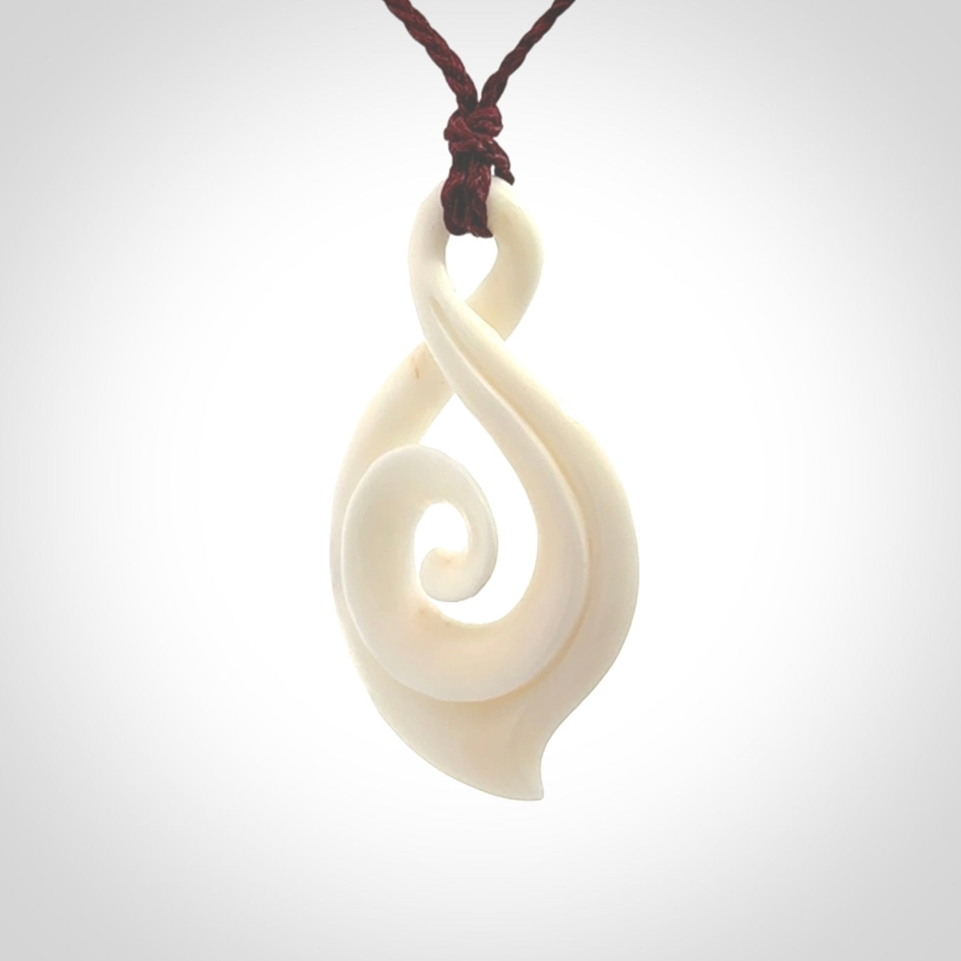 Hand carved twist with koru. Made from natural bone by NZ Pacific. Delivered with an adjustable cord.