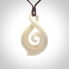 Hand carved twist with koru. Made from natural bone by NZ Pacific. Delivered with an adjustable cord.
