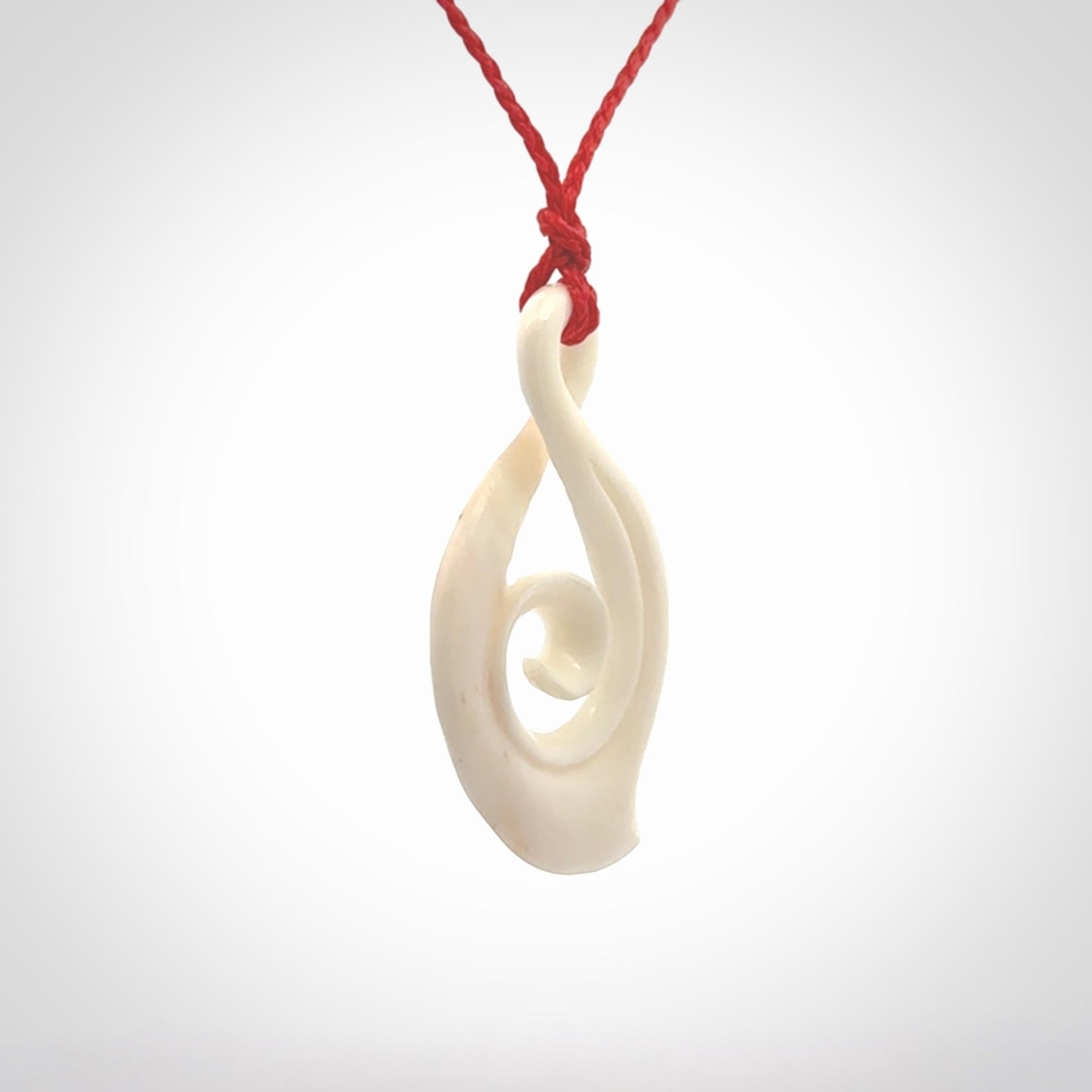 Hand carved twist with koru. Made from natural bone by NZ Pacific. Delivered with an adjustable cord.