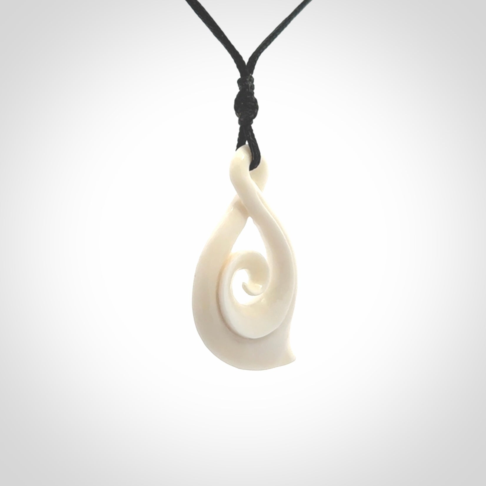 Hand carved twist with koru. Made from natural bone by NZ Pacific. Delivered with an adjustable cord.