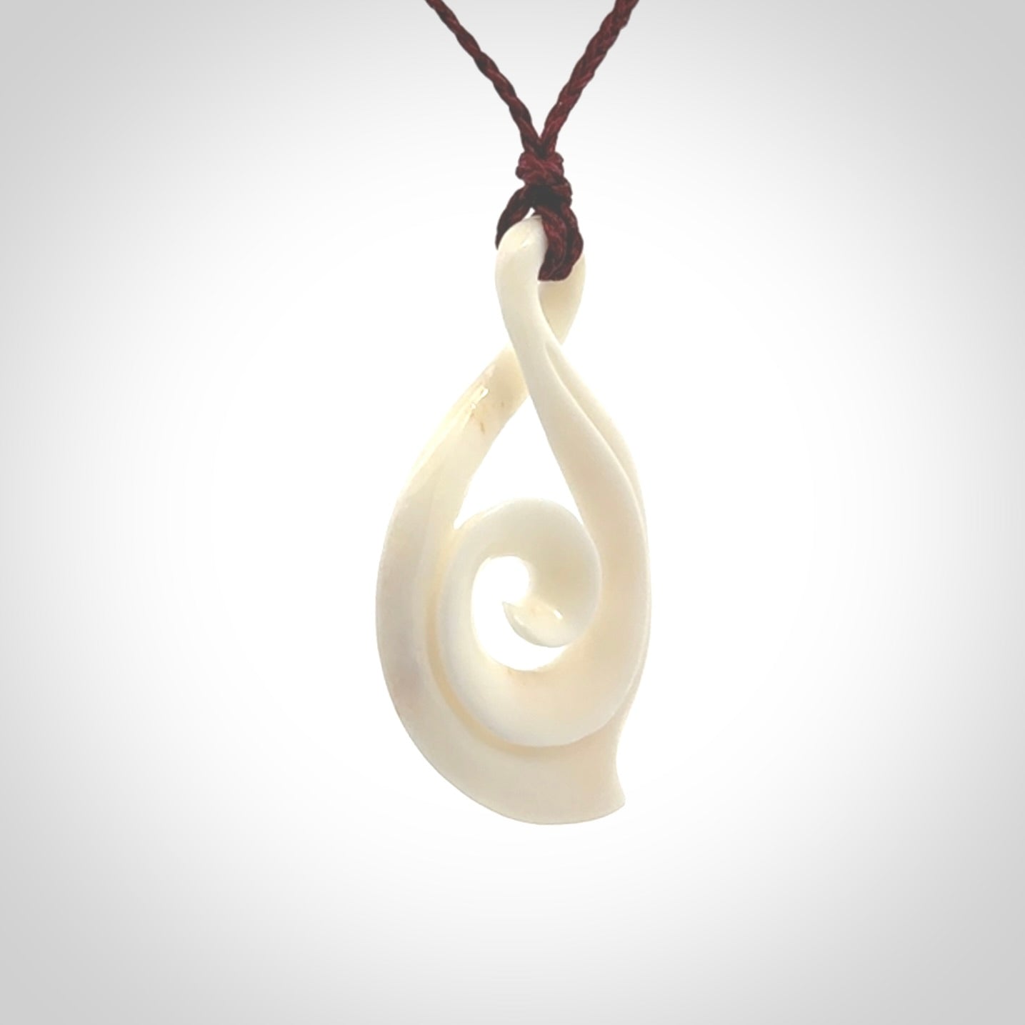 Hand carved twist with koru. Made from natural bone by NZ Pacific. Delivered with an adjustable cord.