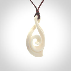 Hand carved twist with koru. Made from natural bone by NZ Pacific. Delivered with an adjustable cord.