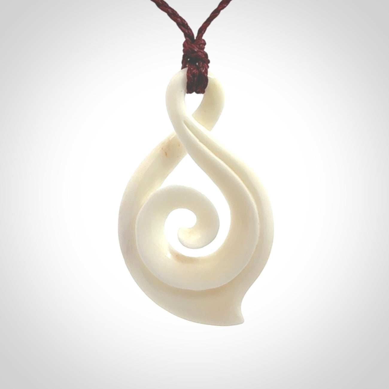 Hand carved twist with koru. Made from natural bone by NZ Pacific. Delivered with an adjustable cord.