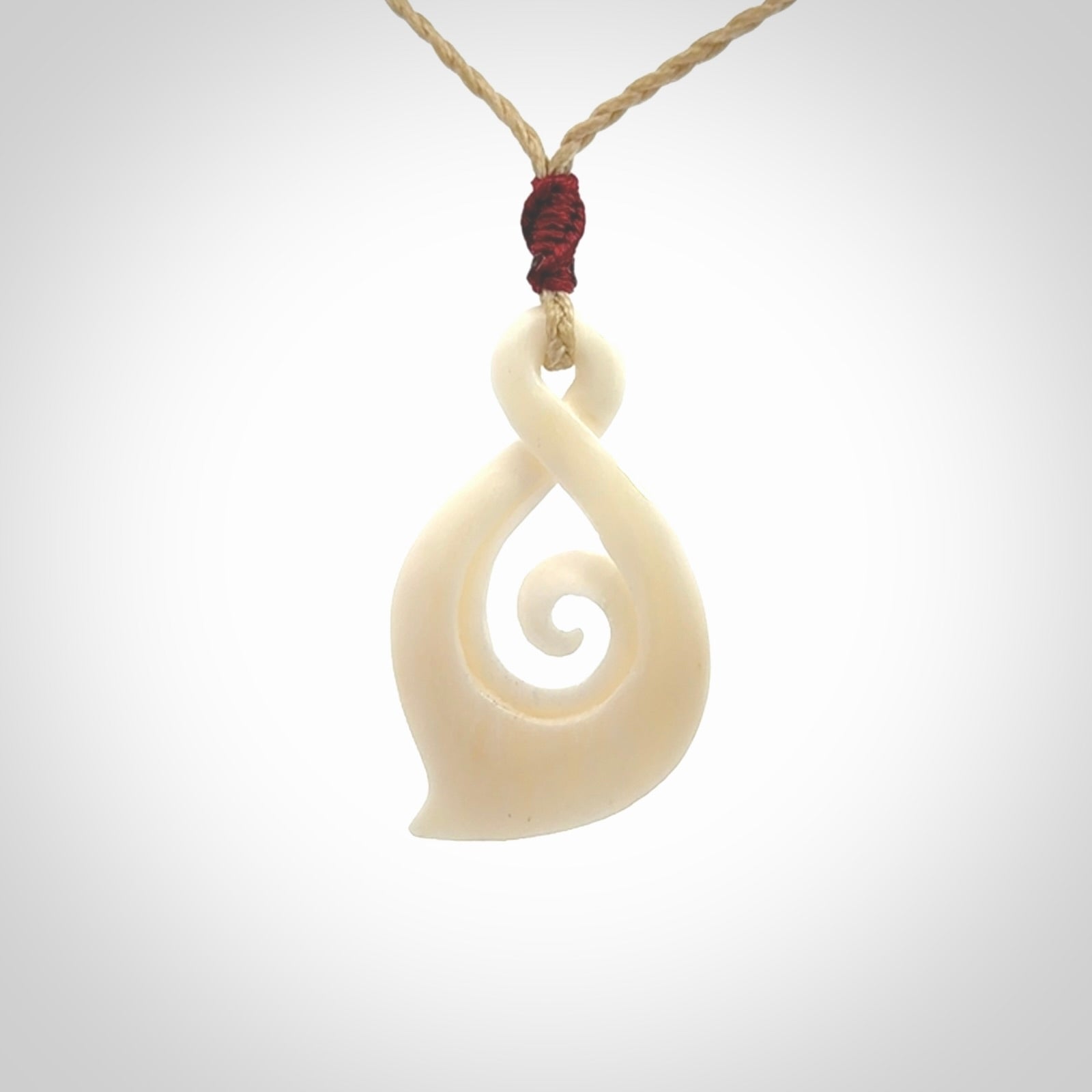 Hand carved twist with koru. Made from natural bone by NZ Pacific. Delivered with an adjustable cord.