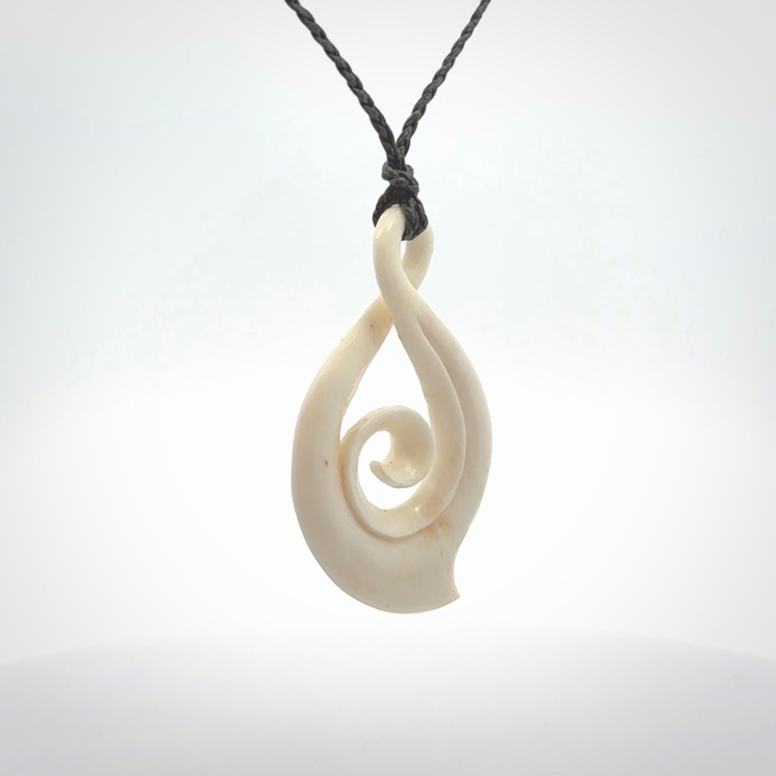 Hand carved twist with koru. Made from natural bone by NZ Pacific. Delivered with an adjustable cord.
