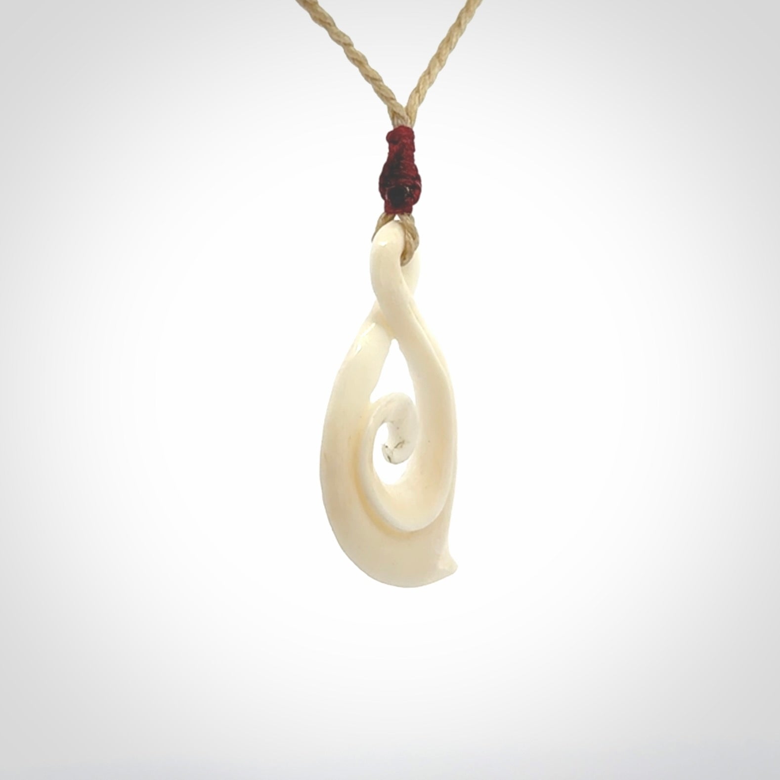 Hand carved twist with koru. Made from natural bone by NZ Pacific. Delivered with an adjustable cord.