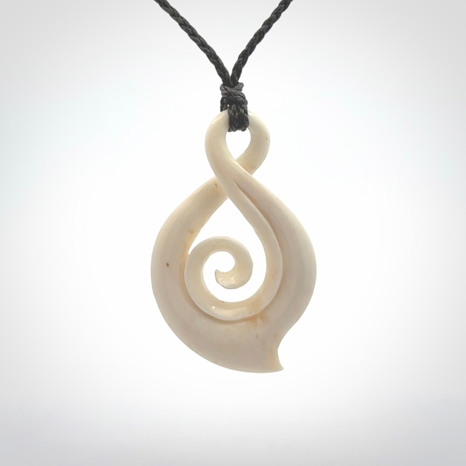 Hand carved twist with koru. Made from natural bone by NZ Pacific. Delivered with an adjustable cord.