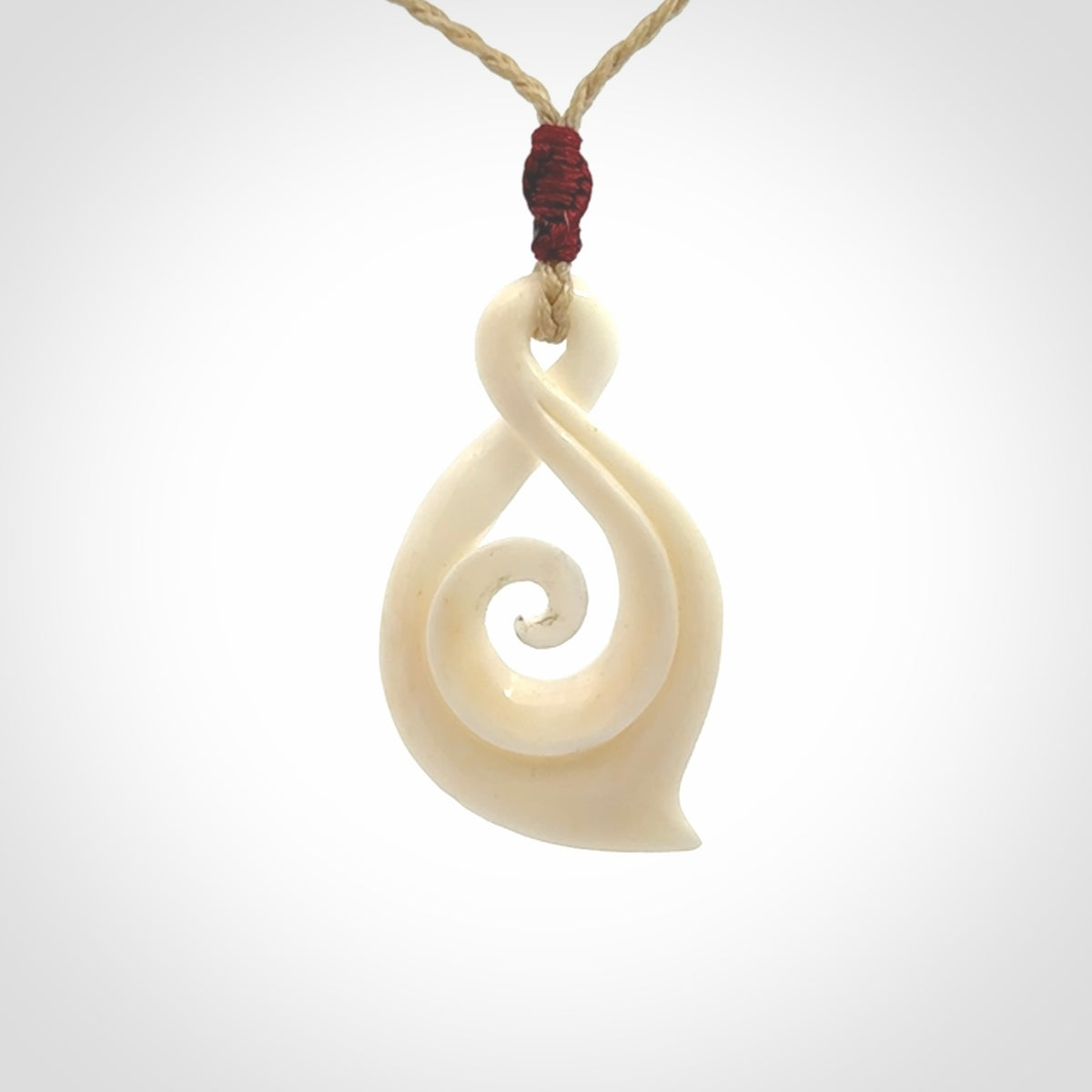 Hand carved twist with koru. Made from natural bone by NZ Pacific. Delivered with an adjustable cord.