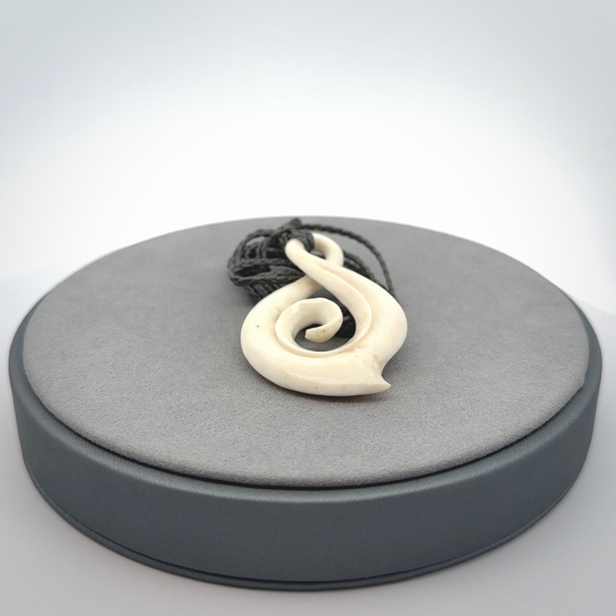 Hand carved twist with koru. Made from natural bone by NZ Pacific. Delivered with an adjustable cord.