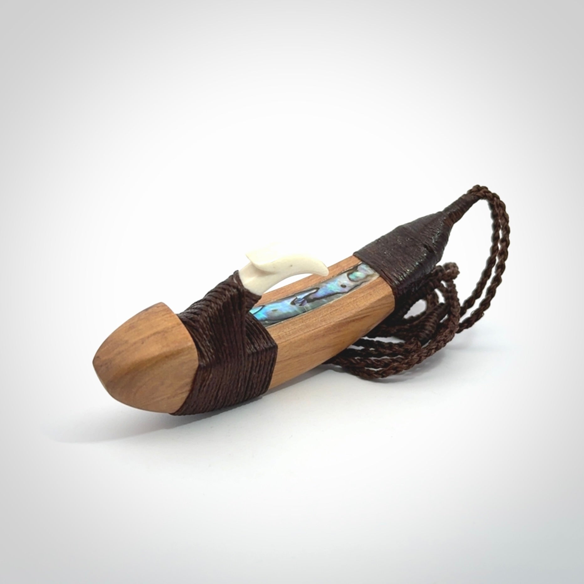 This picture shows a large matau, hook called a pā kahawai. It is carved from bone,  wood, and paua shell. One only, free shipping worldwide. Provided with an adjustable brown cord. Stunning work of Art to Wear by Andrew Doughty.