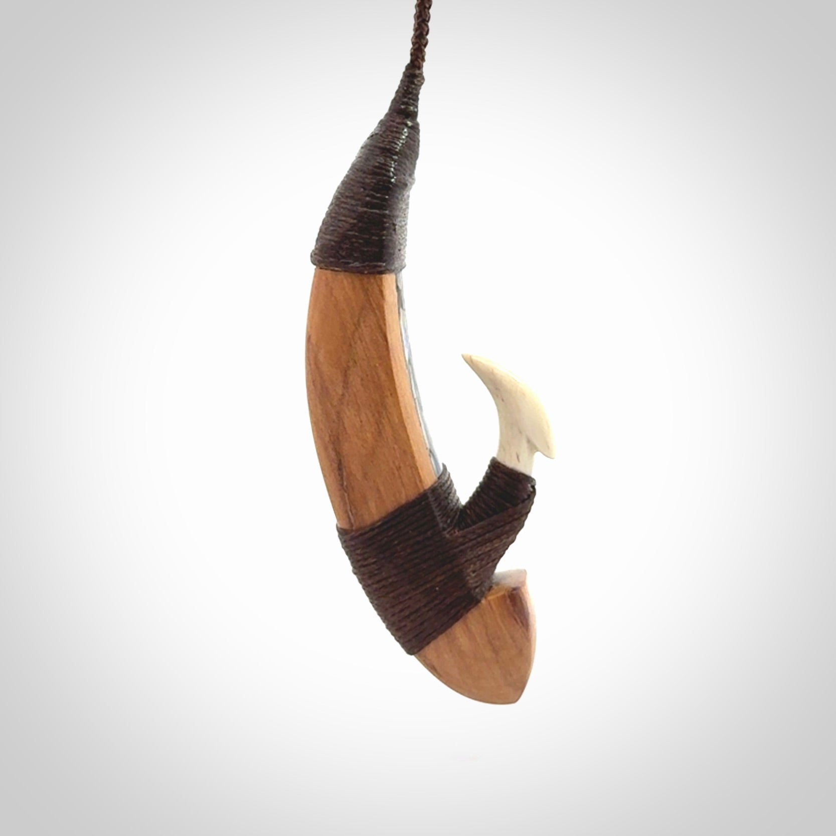 This picture shows a large matau, hook called a pā kahawai. It is carved from bone,  wood, and paua shell. One only, free shipping worldwide. Provided with an adjustable brown cord. Stunning work of Art to Wear by Andrew Doughty.