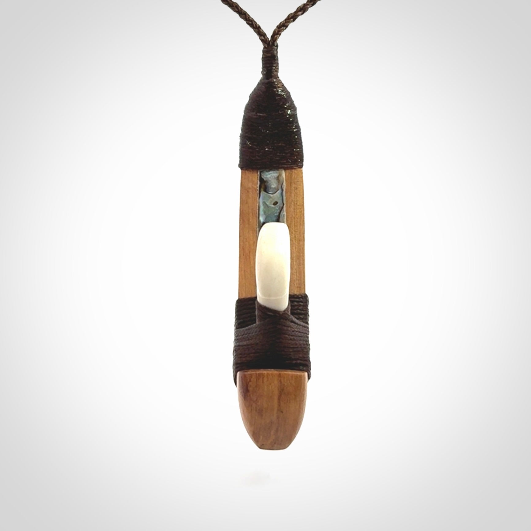 This picture shows a large matau, hook called a pā kahawai. It is carved from bone,  wood, and paua shell. One only, free shipping worldwide. Provided with an adjustable brown cord. Stunning work of Art to Wear by Andrew Doughty.