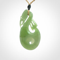 Hand carved New Zealand Inanga jade manaia with koru pendant. Carved from beautiful New Zealand Jade for NZ Pacific by Ross Crump. Unique jade jewellery for sale online. Provided with an adjustable tan cord.