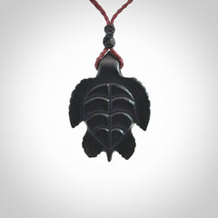 This picture shows a hand carved black jade turtle pendant. It is polished to a soft shine and has quite a lot of detail carved into the jade. The cord is a hand plaited burgundy, waxed polyester. Carved by NZ Pacific.