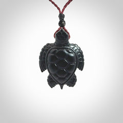 This picture shows a hand carved black jade turtle pendant. It is polished to a soft shine and has quite a lot of detail carved into the jade. The cord is a hand plaited burgundy, waxed polyester. Carved by NZ Pacific.
