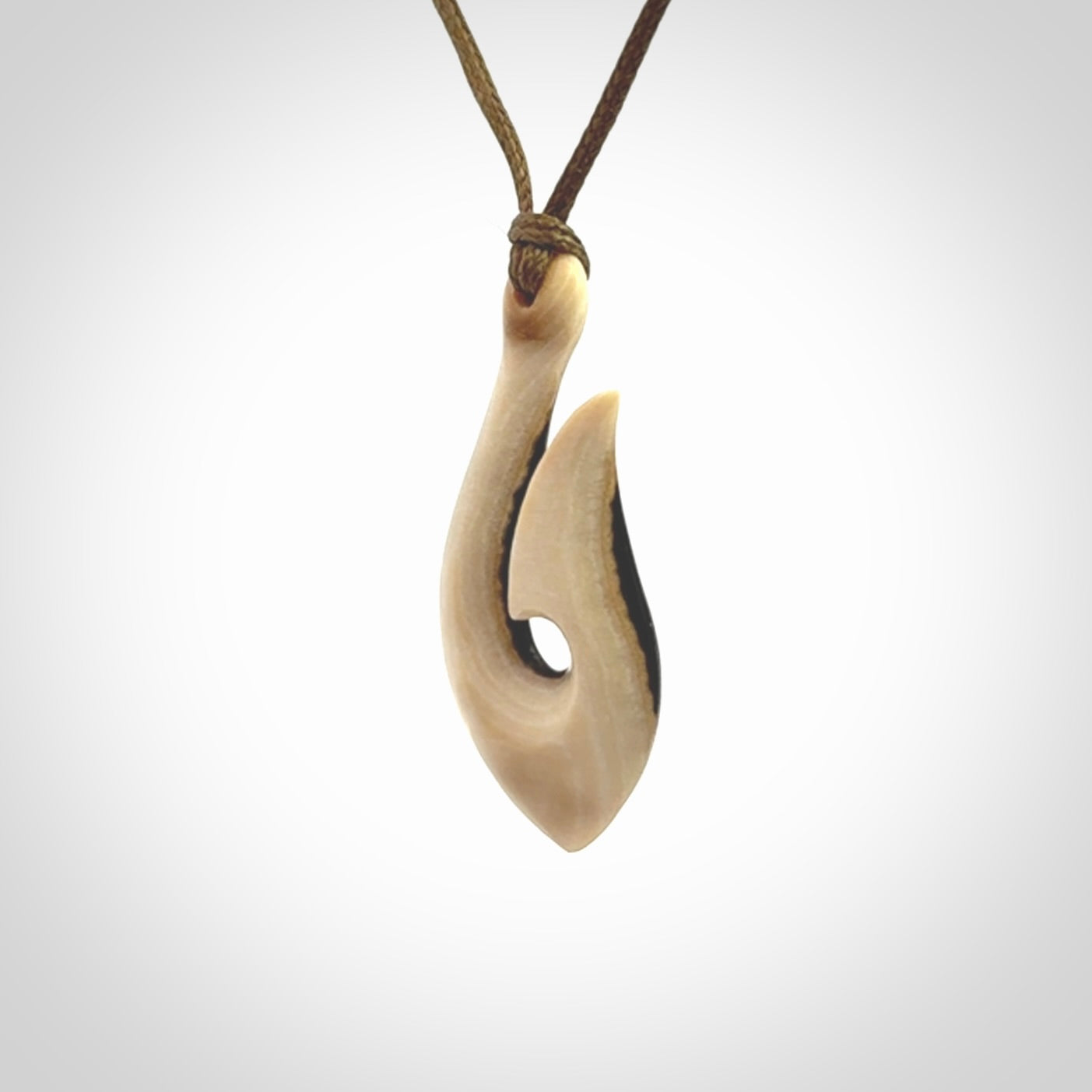 A fish hook necklace (hei-matau) hand-carved in a traditional style from Woolly Mammoth Tusk. These are glorious pieces of art to wear. Provided with adjustable cords and packaged in a woven kete pouch. Delivered with express courier.