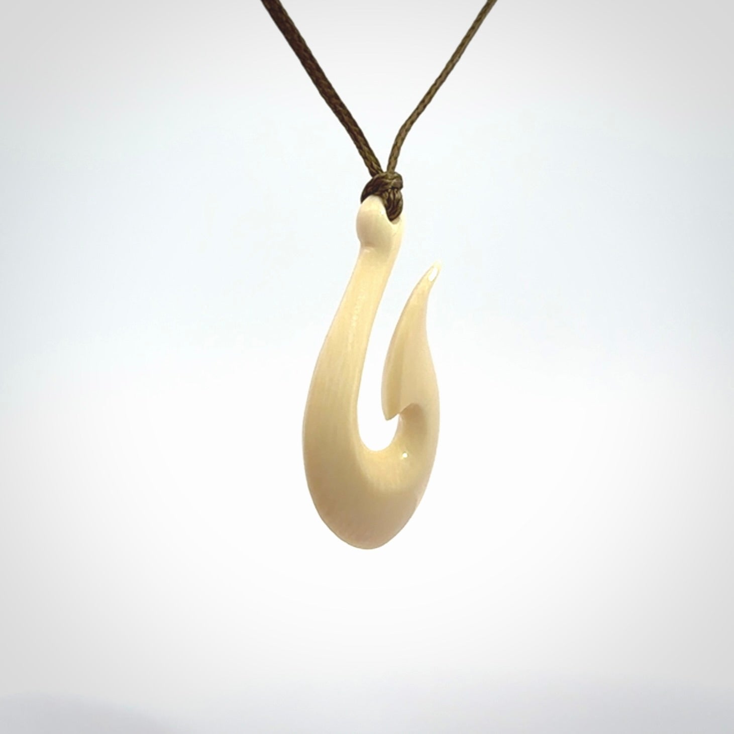 A fish hook necklace (hei-matau) hand-carved in a traditional style from Woolly Mammoth Tusk. These are glorious pieces of art to wear. Provided with adjustable cords and packaged in a woven kete pouch