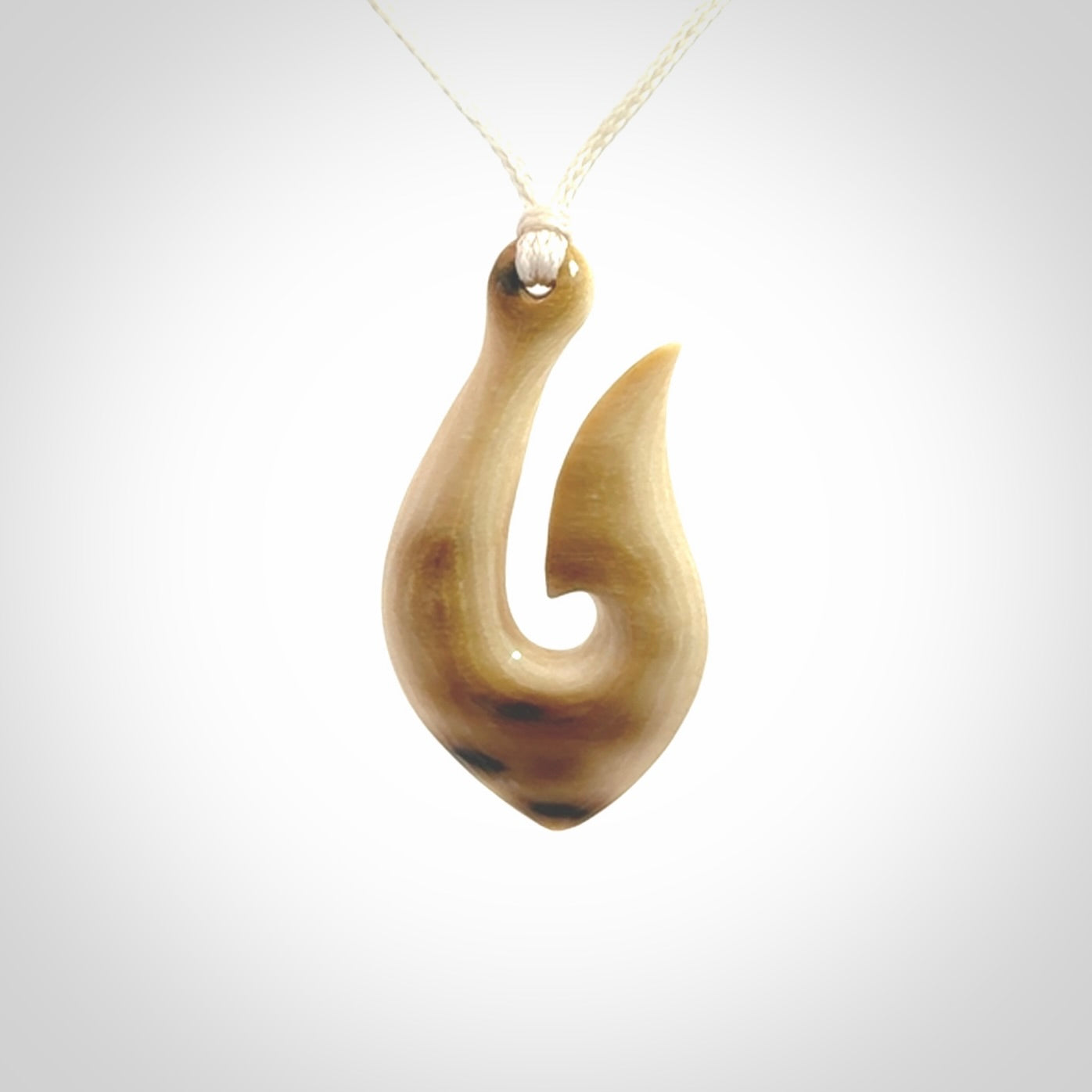 A fish hook necklace (hei-matau) hand-carved in a traditional style from Woolly Mammoth Tusk. These are glorious pieces of art to wear. Provided with adjustable cords and packaged in a woven kete pouch. Delivered with express courier.