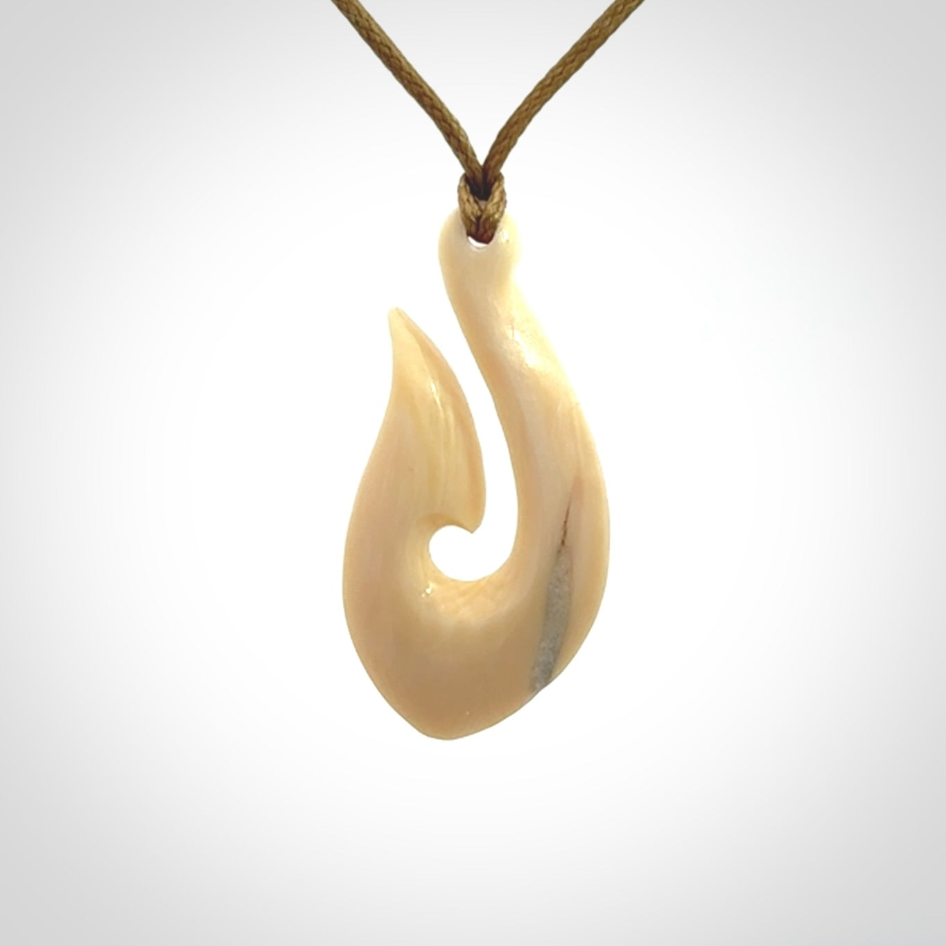 A fish hook necklace (hei-matau) hand-carved in a traditional style from Woolly Mammoth Tusk. These are glorious pieces of art to wear. Provided with adjustable cords and packaged in a woven kete pouch