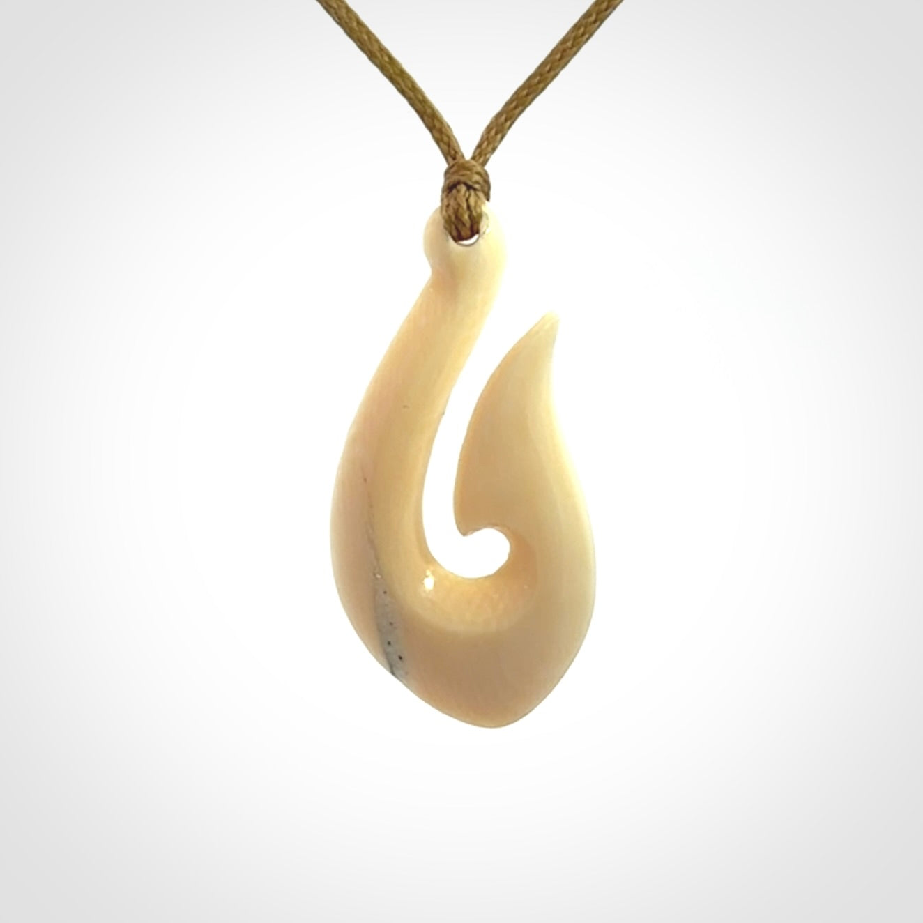 A fish hook necklace (hei-matau) hand-carved in a traditional style from Woolly Mammoth Tusk. These are glorious pieces of art to wear. Provided with adjustable cords and packaged in a woven kete pouch