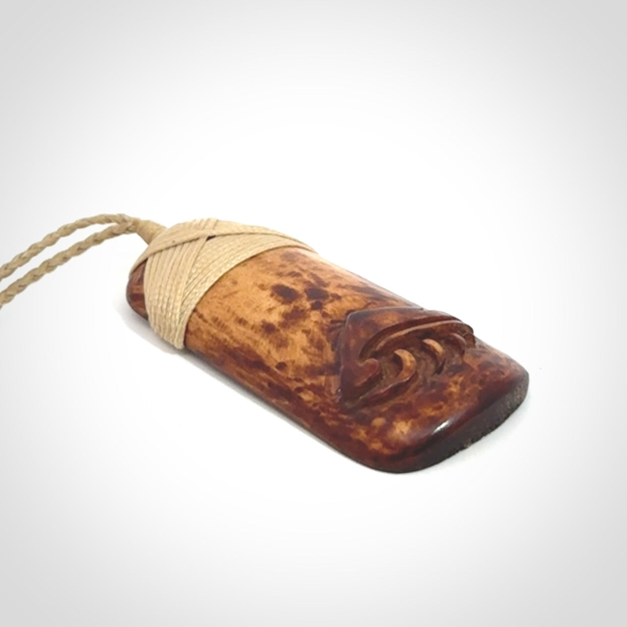 A hand carved bone toki pendant with NZ Pacific logo engraving. These have been stained with our home made tea dye. Unique hand made jewellery from New Zealand Pacific.