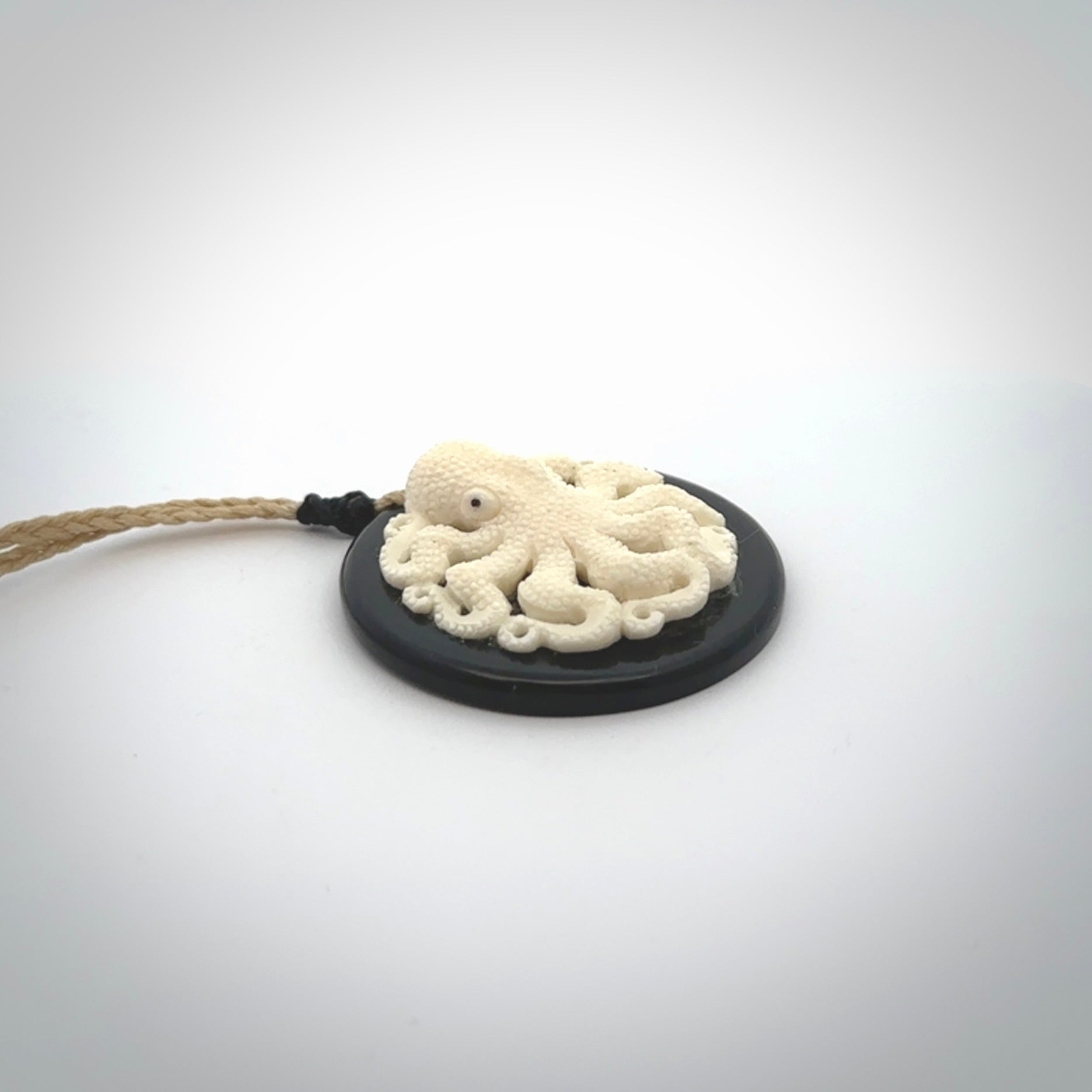 This is a magnificent hand carved octopus pendant. Hand carved in Bone with Black Jade. Provided with an adjustable cord. Hand made octopus pendant.