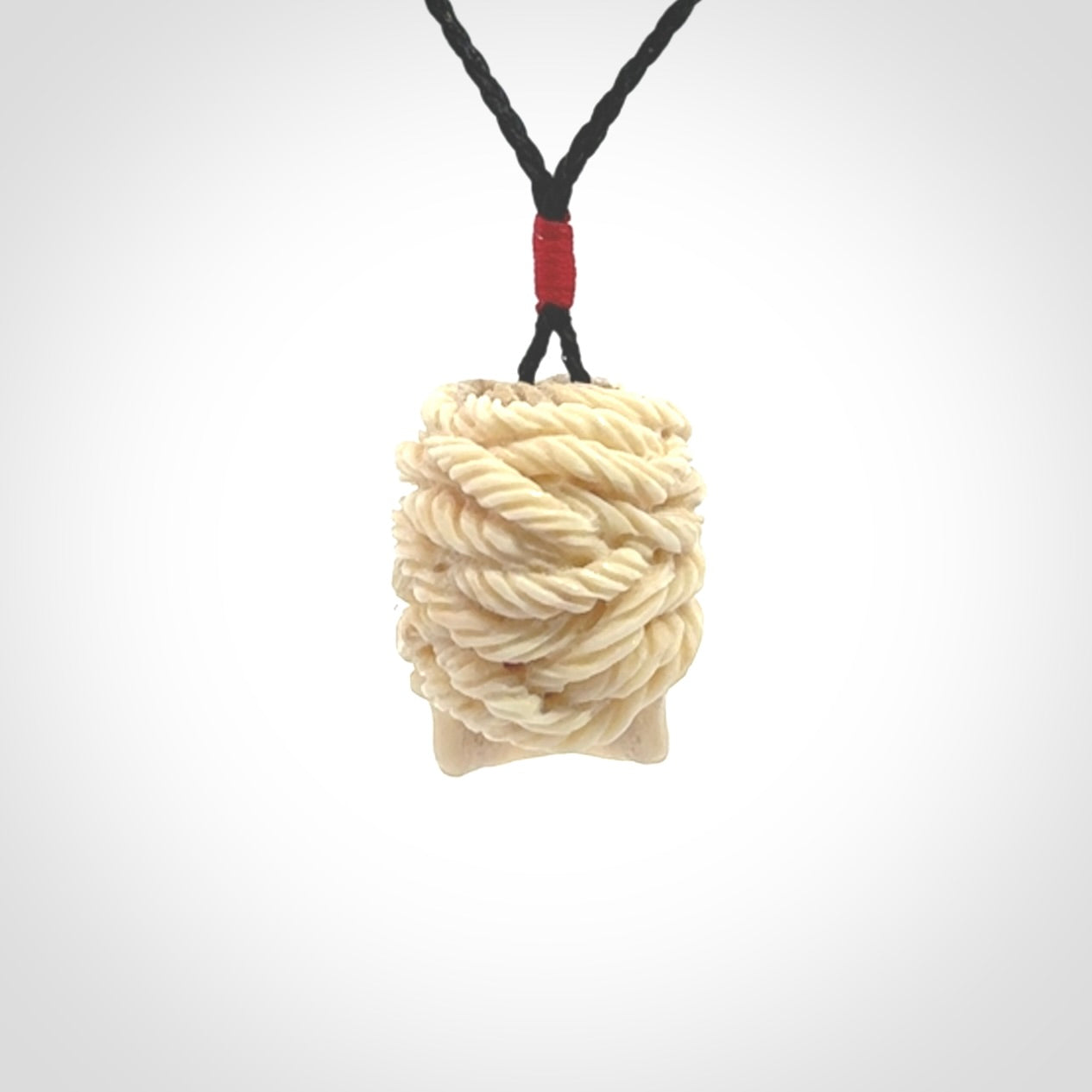 This picture shows a medium sized Deer Antler Bone pirate skull pendant that we have hand carved. The cord is a black colour and has a small red binding just above the pendant.