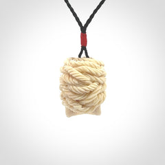 This picture shows a medium sized Deer Antler Bone pirate skull pendant that we have hand carved. The cord is a black colour and has a small red binding just above the pendant.