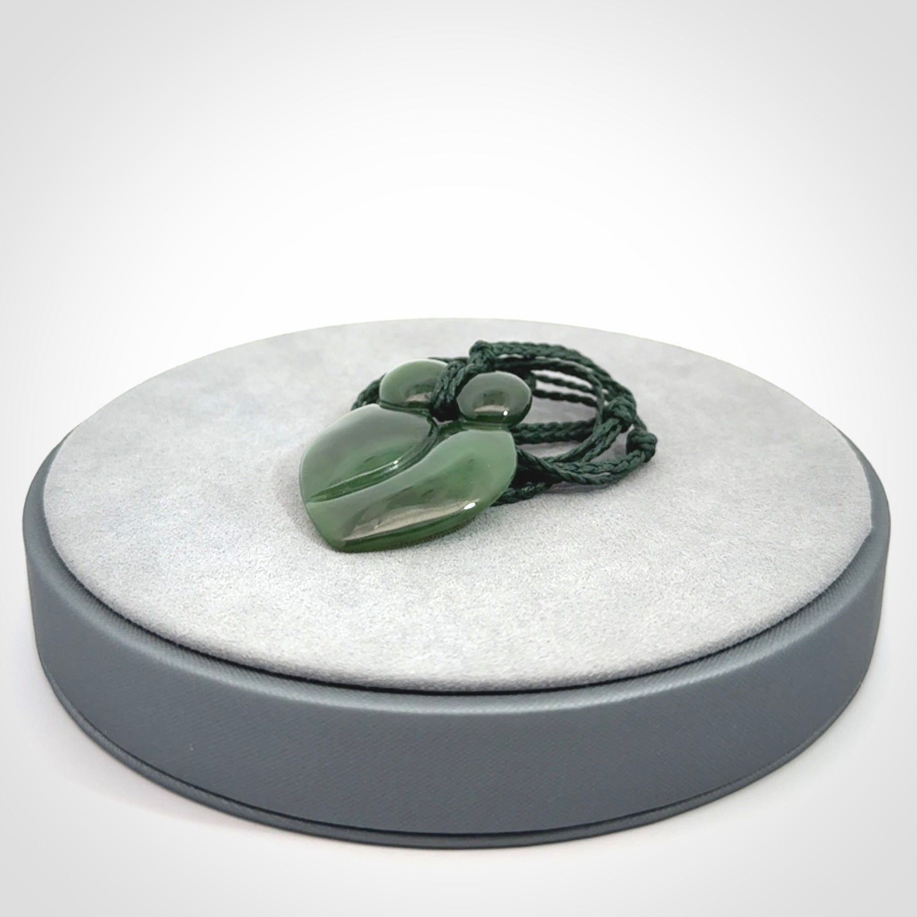 This picture shows a stylised couple in a close embrace sharing a kiss. The pendant is hand carved from a bright faultless piece of British Columbian jade. The cord is a 3-ply plaited green which is adjustable.
