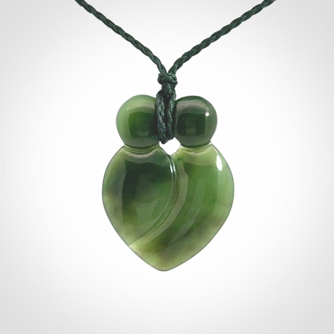 This picture shows a stylised couple in a close embrace sharing a kiss. The pendant is hand carved from a bright faultless piece of British Columbian jade. The cord is a 3-ply plaited green which is adjustable.