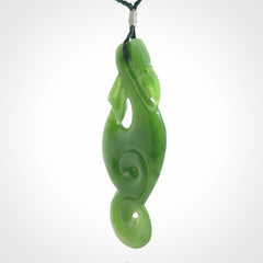 This pendant is a beautiful large New Zealand Auhunga green jade manaia pendant with koru. It has the head of a bird and the tail of a fish and also two koru carved into the body. It is carved by Ross Crump here in New Zealand. Provided with an adjustable manuka green cord.