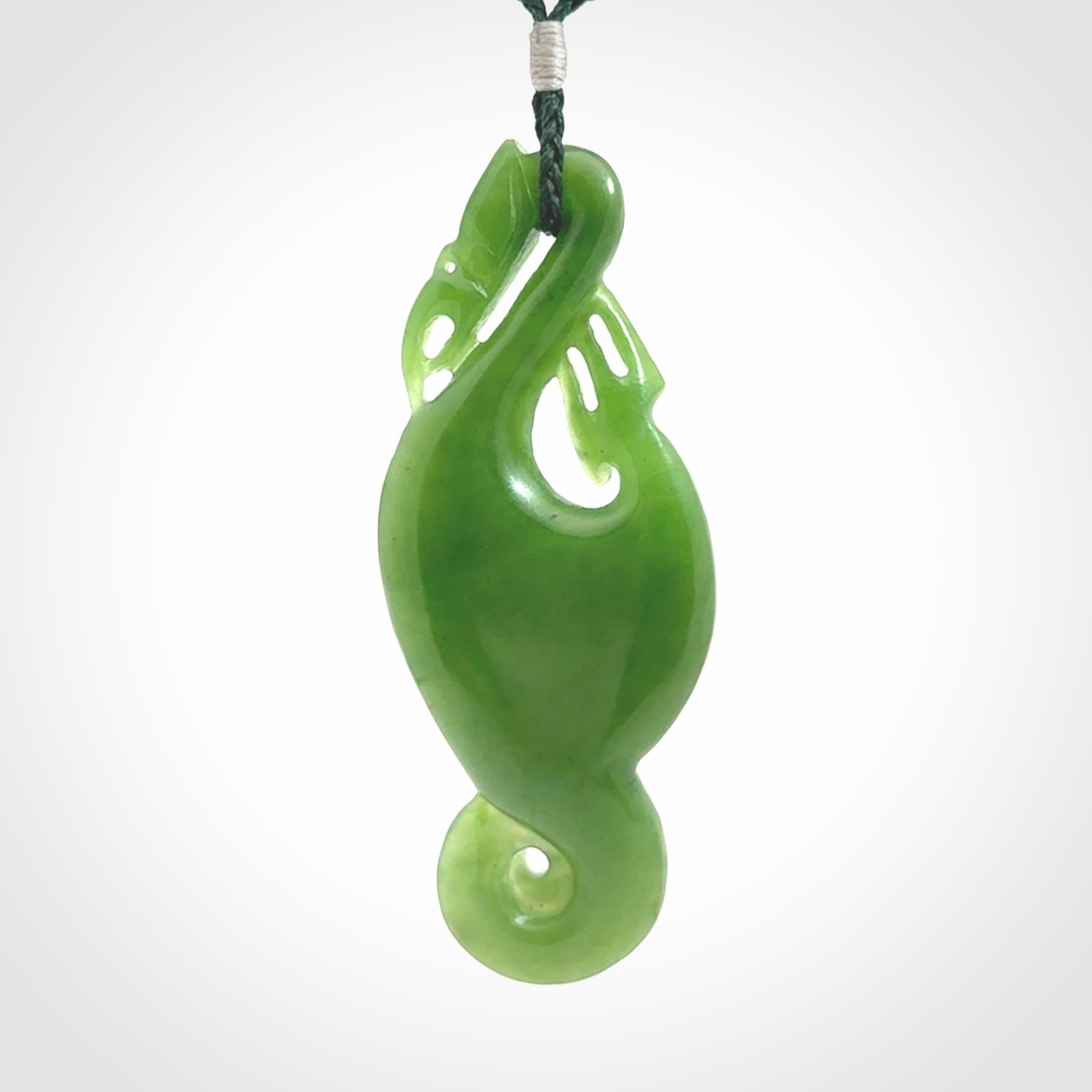 This pendant is a beautiful large New Zealand Auhunga green jade manaia pendant with koru. It has the head of a bird and the tail of a fish and also two koru carved into the body. It is carved by Ross Crump here in New Zealand. Provided with an adjustable manuka green cord.