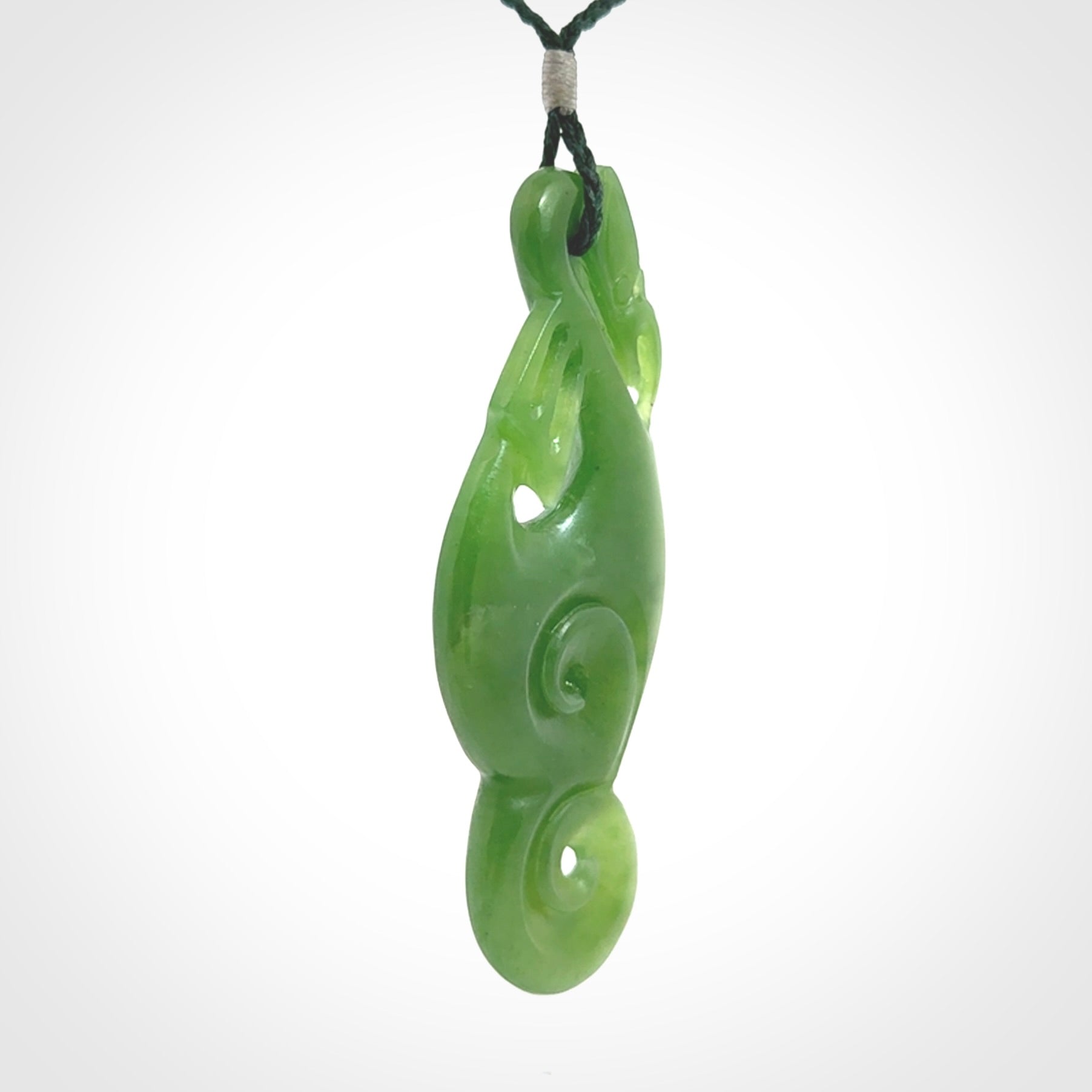 This pendant is a beautiful large New Zealand Auhunga green jade manaia pendant with koru. It has the head of a bird and the tail of a fish and also two koru carved into the body. It is carved by Ross Crump here in New Zealand. Provided with an adjustable manuka green cord.